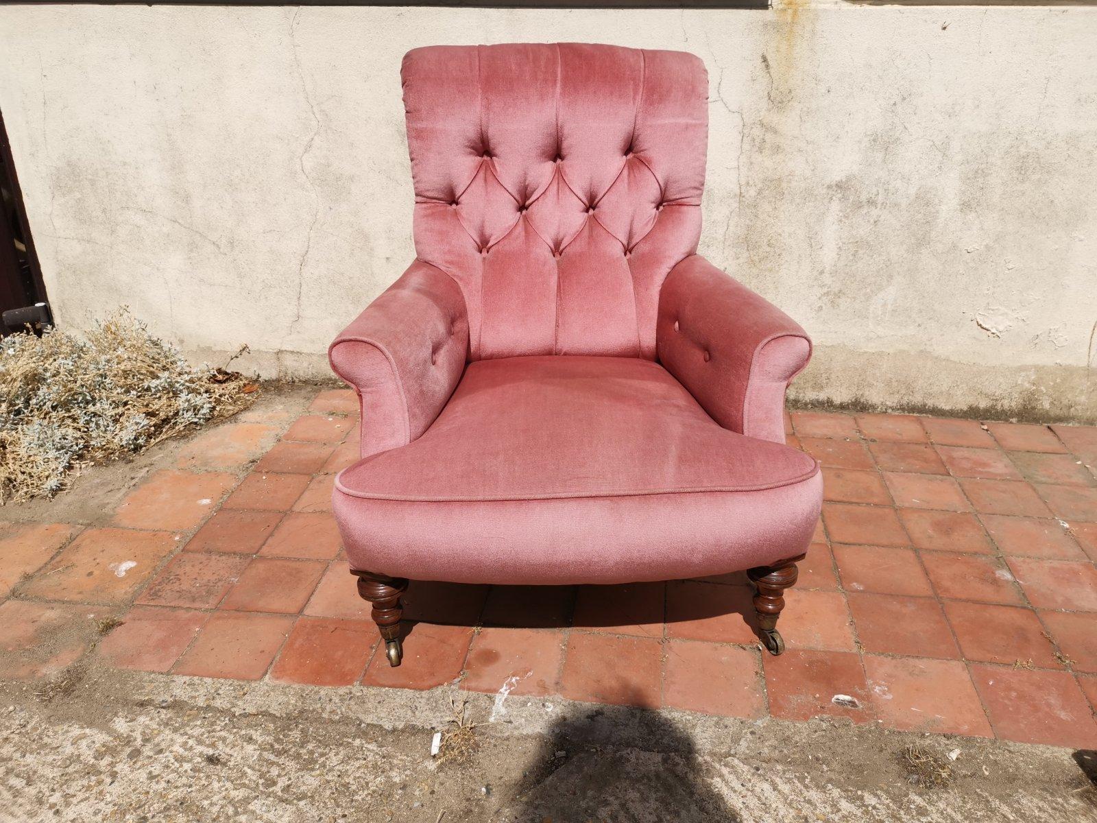 Gillows or possibly Howards.
A good quality comfy English Victorian roll back pink traditionally upholstered button-back fireside armchair with a wide curved front and hand-stitched pipping, on turned Walnut legs with the original brass