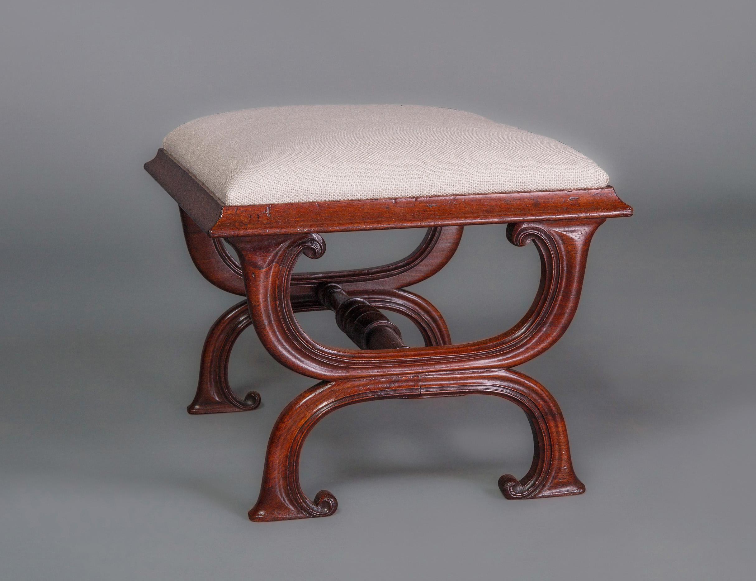 A very attractive stool in a variation of the x-frame design developed in the early Regency period by the renowned firm of Gillows of Lancaster with a well turned stretchers, carved legs and the unusual feature of inturned feet.