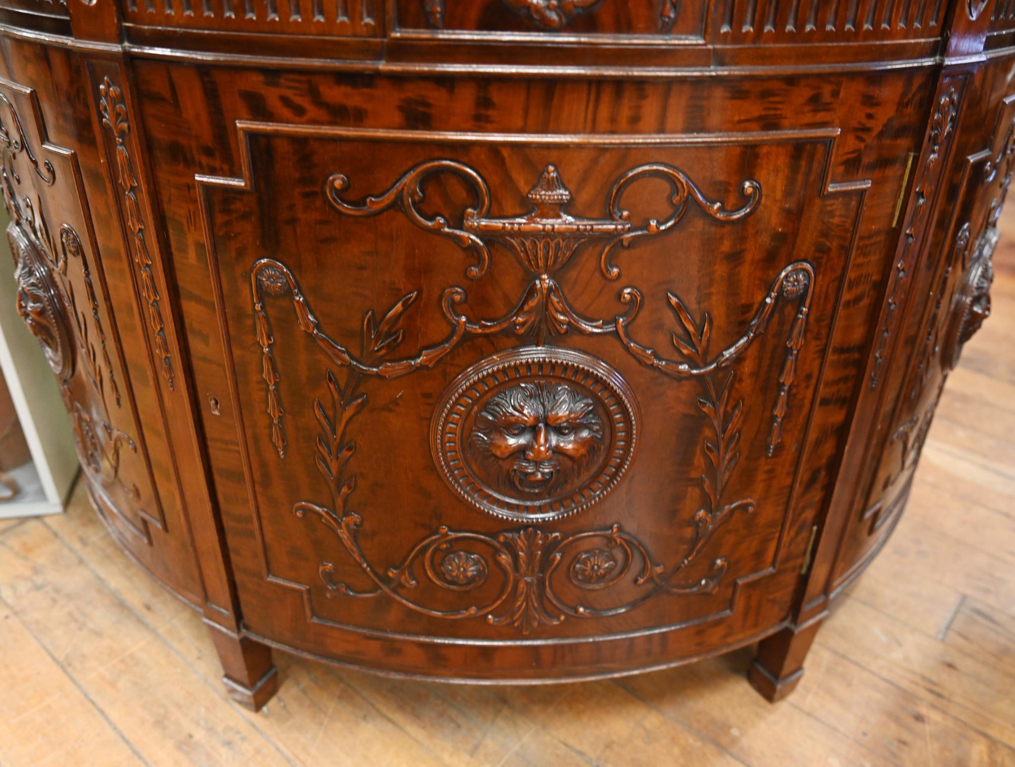Vous voyez ici un magnifique meuble d'appoint demi-lune en acajou à la manière de Gillows.
Motifs sculptés et bord du fond de tarte
Les détails sculptés en relief sont exquis, notamment un masque de lion, des urnes, des festons et des reliefs