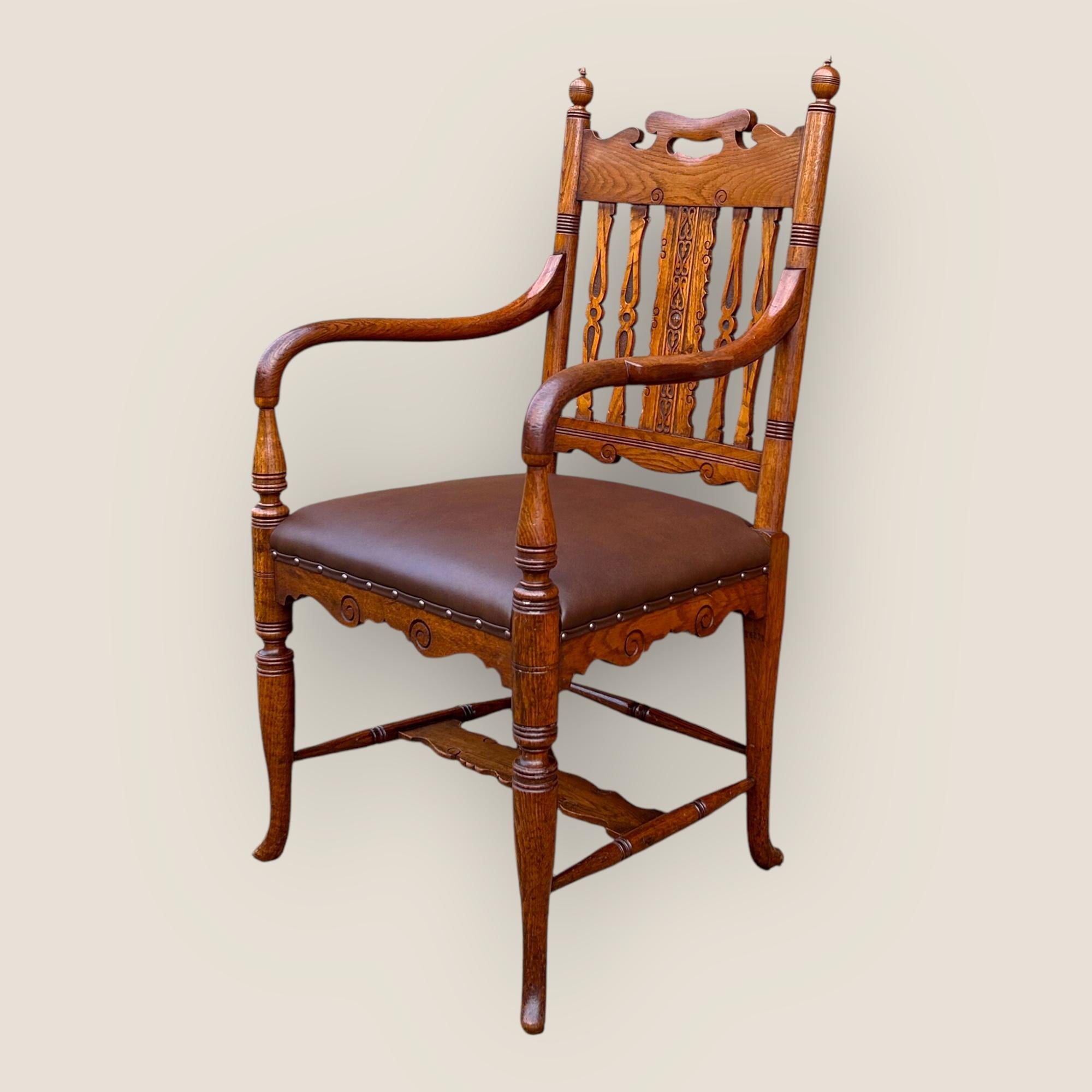 A Gillows Late Victorian Golden Oak Desk Chair attributed to Bruce James Talbert. This fine chair has a carved back with detailed geometric designs, turned legs, a carved finial on top of both sides, a great condition upholstered brown seat and