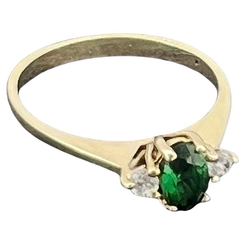 Performed in 9K Yellow Gold,
the ring is centring an Oval Gilson 

Synthetic Emerald of 0.43ct approx. (6mm x 4mm)
of magnificent vivid Grass Green colour & 
excellent clarity, claw-set  

Flanked by 2 round diamonds, 
totalling 0.10ct approx.
Shank