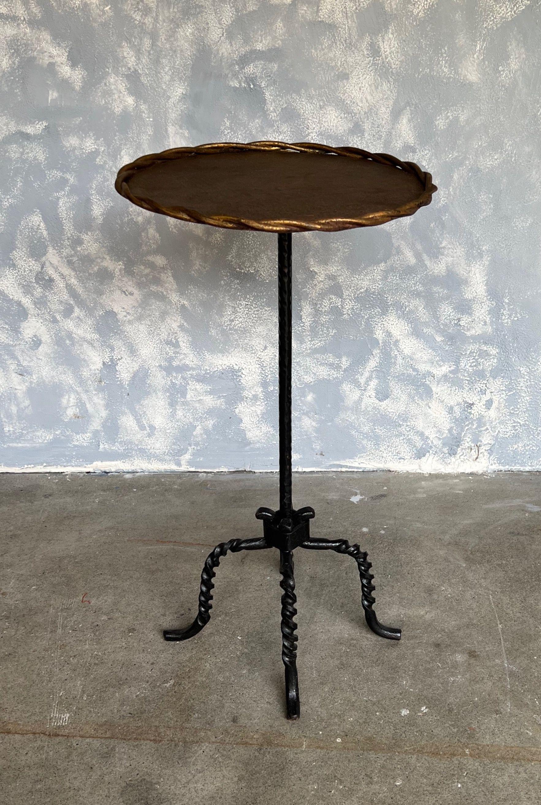 This distinctive drinks table features an extraordinary tripod design with heavily twisted legs in a dark painted finish. The table is designed with a circular central stem that supports a round top, encased by a double braided frame, ensuring your