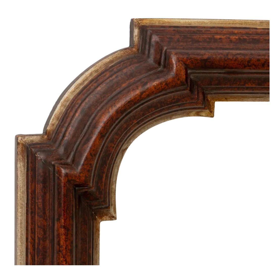 A shaped wall mirror with a faux tortoiseshell painted finish to the frame with gilt details.  