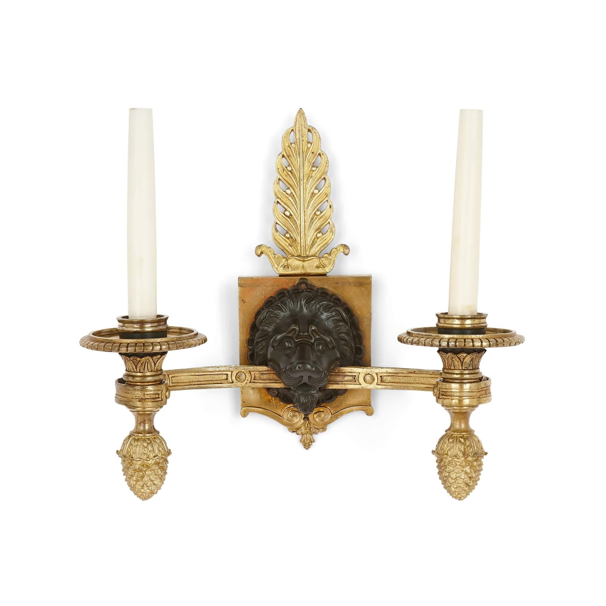 Gilt and patinated bronze Empire-style wall lights 
French, Early 20th century
Height 35cm, width 36cm, depth 20cm

This pair of wall lights or sconces are modeled in the opulent French Empire style. Each takes the form of two-light gilt bronze