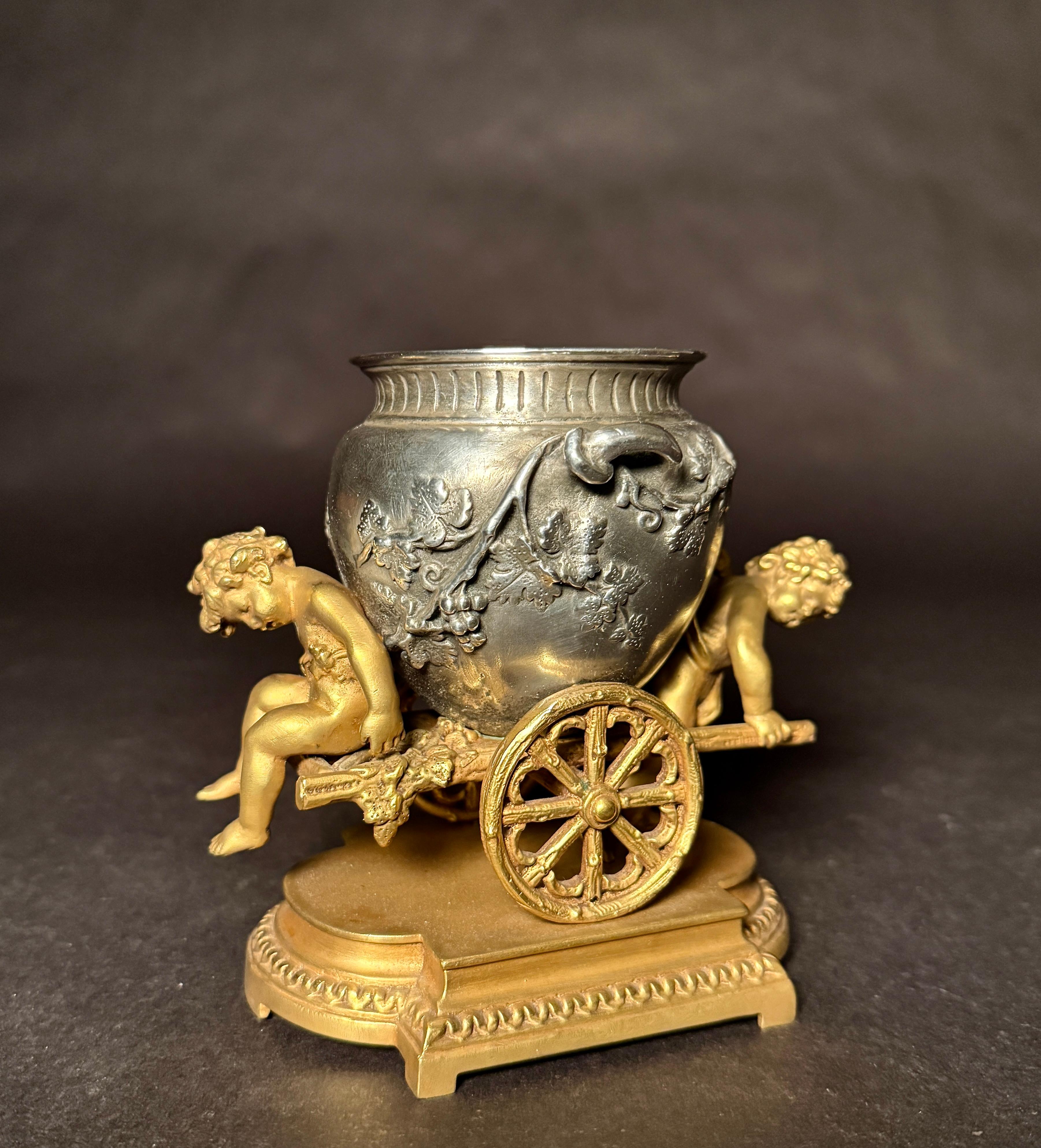 Eugene Provost (1836-1885) France, 19th century, a charming gilt and silvered bronze sculpture depicting two putti moving a chariot with grapes and vines, on a rectangle shaped base.