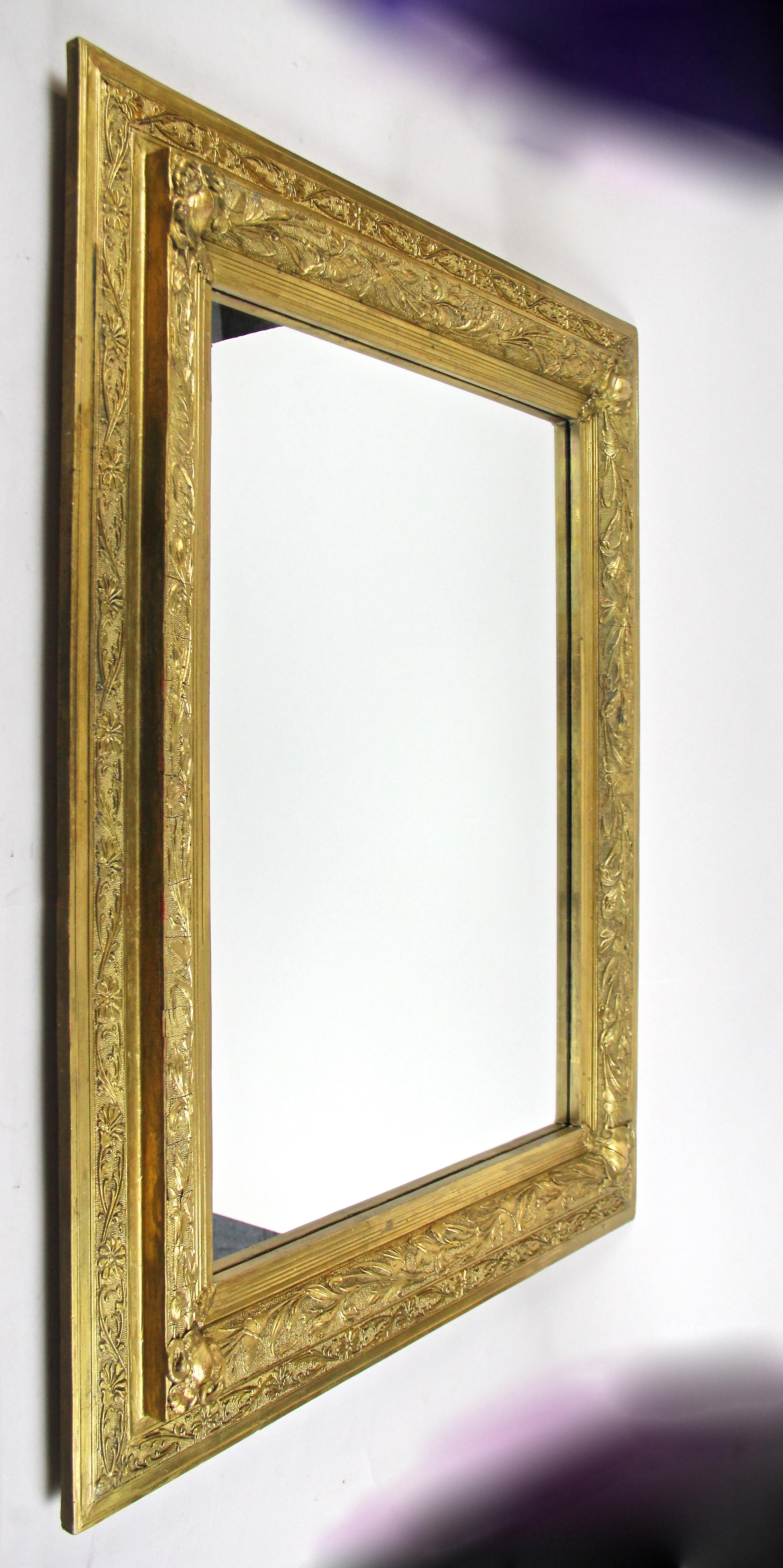 Stunning gilt Art Nouveau wall mirror out of France from the beginning of the 20th century around 1900. This large French golden mirror impresses with a broad frame work adorned by artfully processed floral design elements and lovely butterflies -