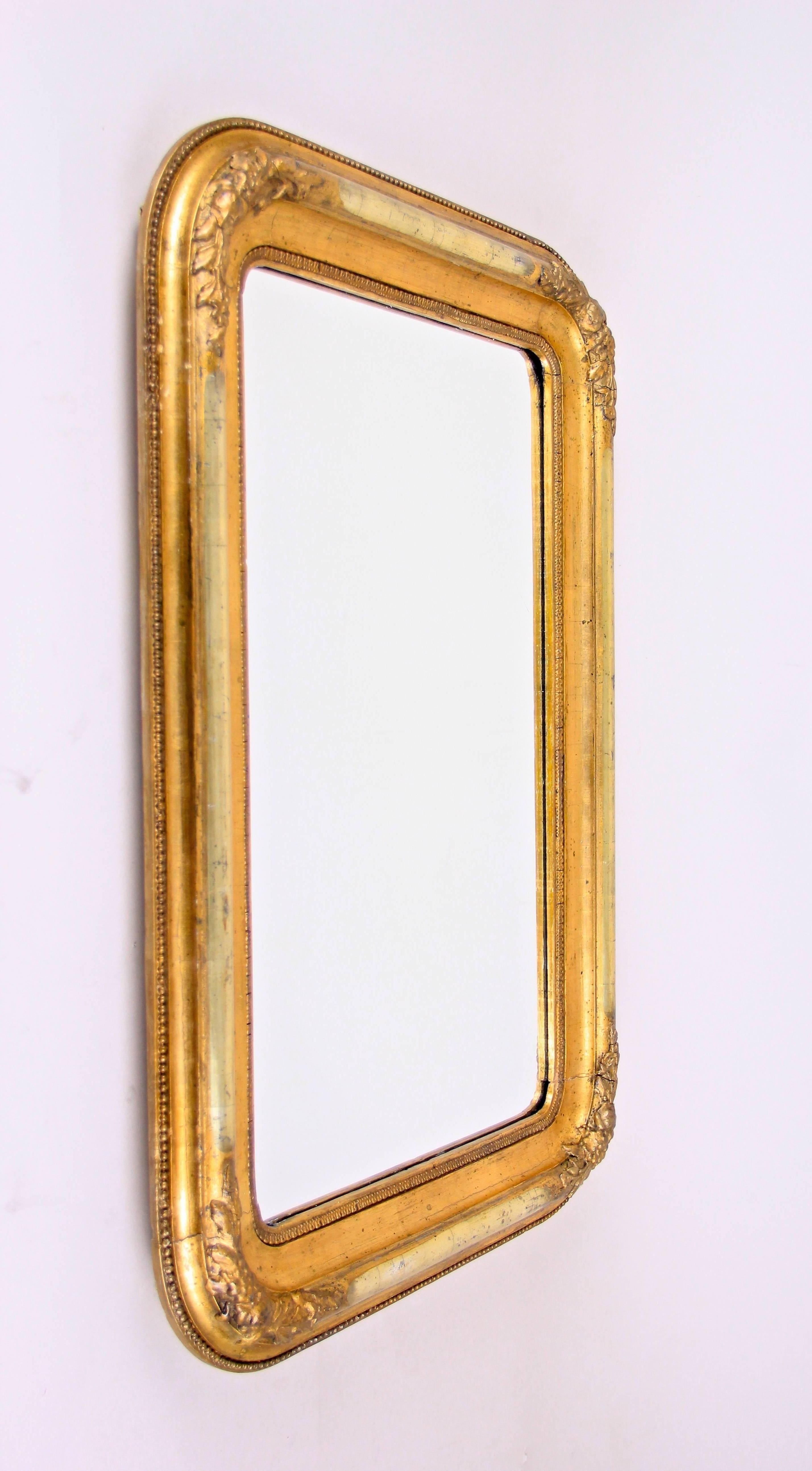 Exclusive gilt Biedermeier wall mirror with silvered half rods from the period circa 1840 in Austria. Impressing with beautiful floral stucco works, silver plated half rods and rounded corners, this precious frame was restored by our experts with