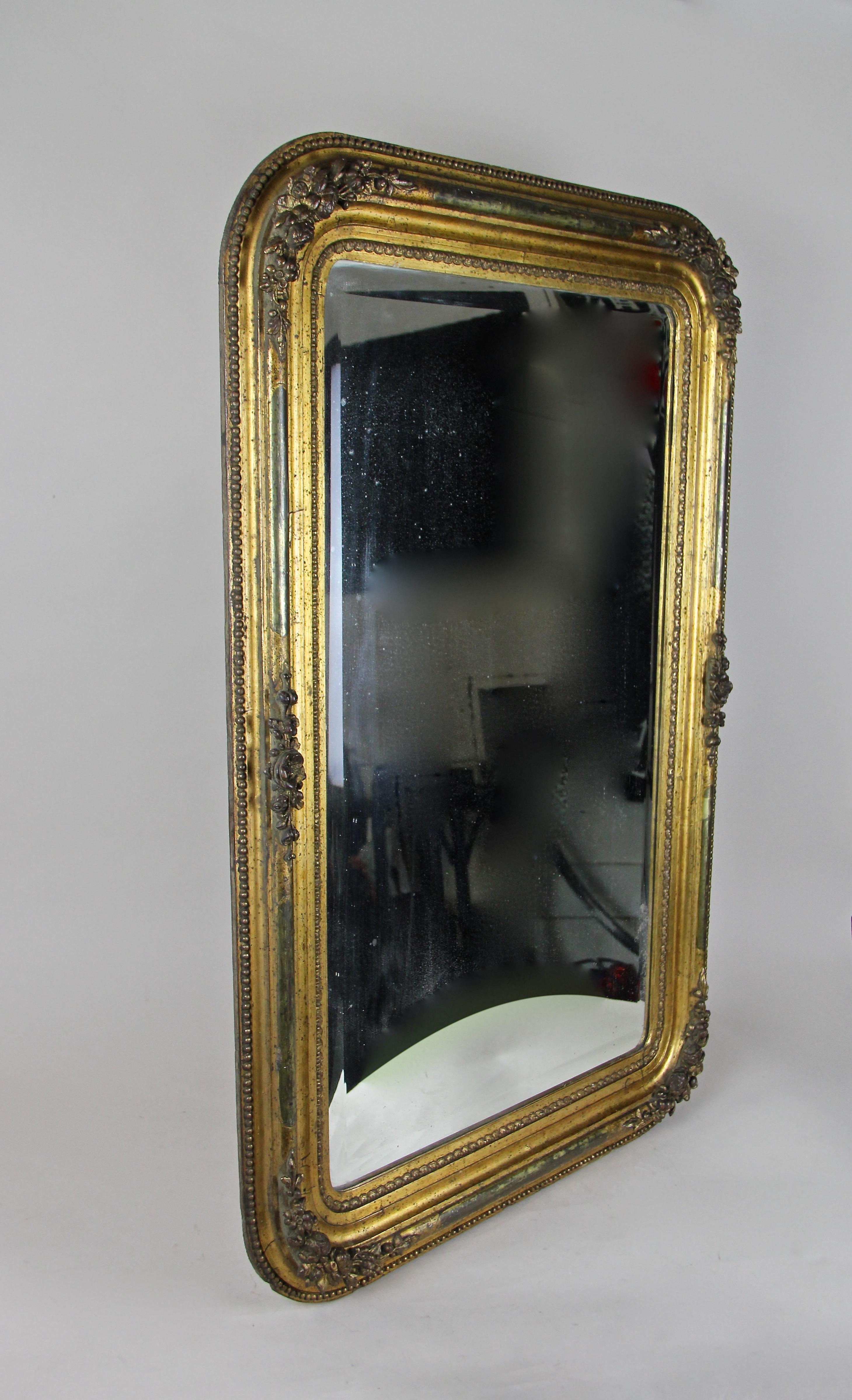 Charming gilt Biedermeier wall mirror from the period around 1840 in Austria. Standing out with its lovely floral stucco work, silver plated half rods (abraded) and rounded corners, this frame was restored by our experts while taking greatest care