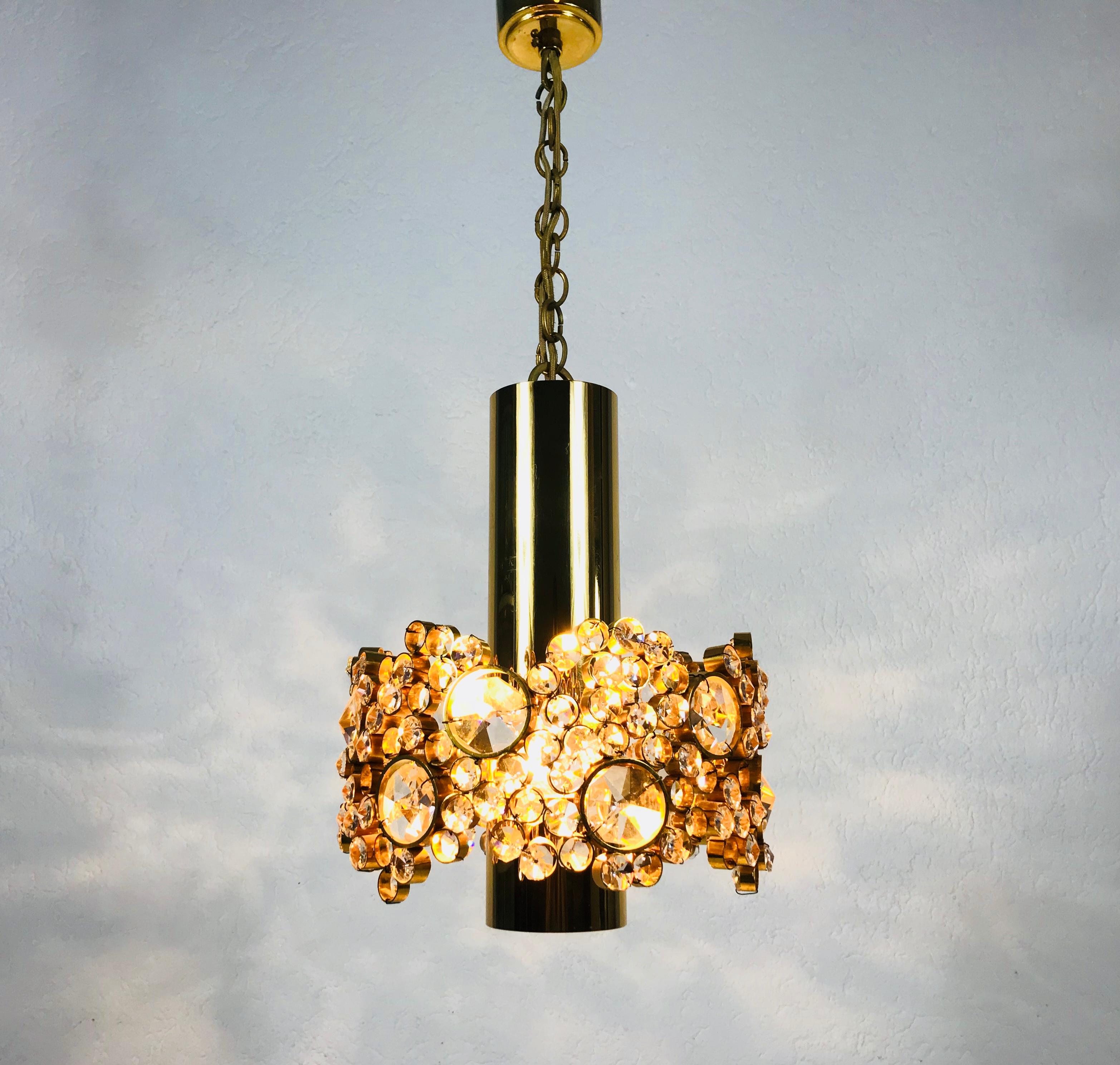Eine außergewöhnliche Pendelleuchte von Palwa, die in den 1970er Jahren in Deutschland hergestellt wurde. Die Lampe hat ein sehr elegantes Design. Er ist in der Zeit des Hollywood Regency angesiedelt. Runder vergoldeter Messingkörper mit einer