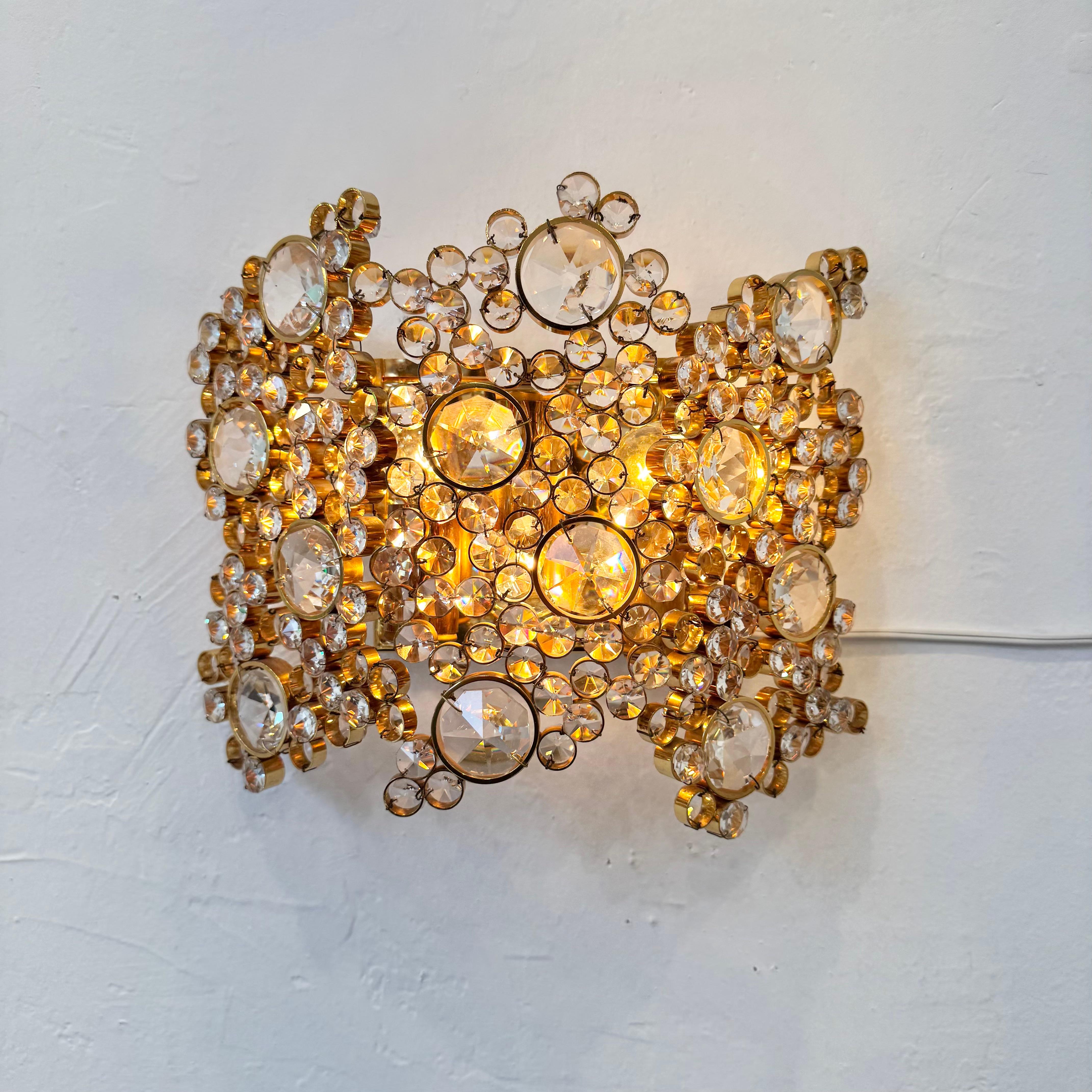 Este brillante candelabro atraerá todas las miradas. Fabricado en la Alemania de los años 60 por Palwa, presenta latón dorado y cristal tallado facetado. Recordando a un racimo de burbujas, docenas de piedras redondas talladas en cristal se esparcen