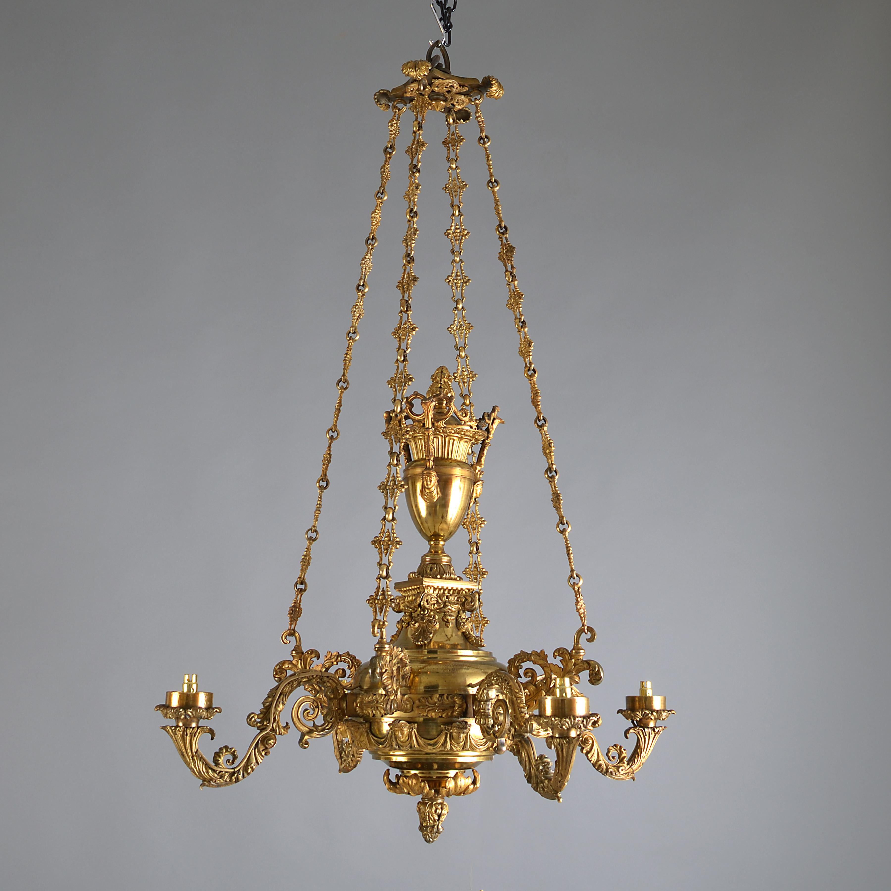 A William IV gilt-brass four-branch chandelier by Messenger & Sons, circa 1835.

Stamped MESSENGER 
The body surmounted by an urn, the arms cast with scrolling acanthus, with a frieze of classical heads linked by drapery swags.