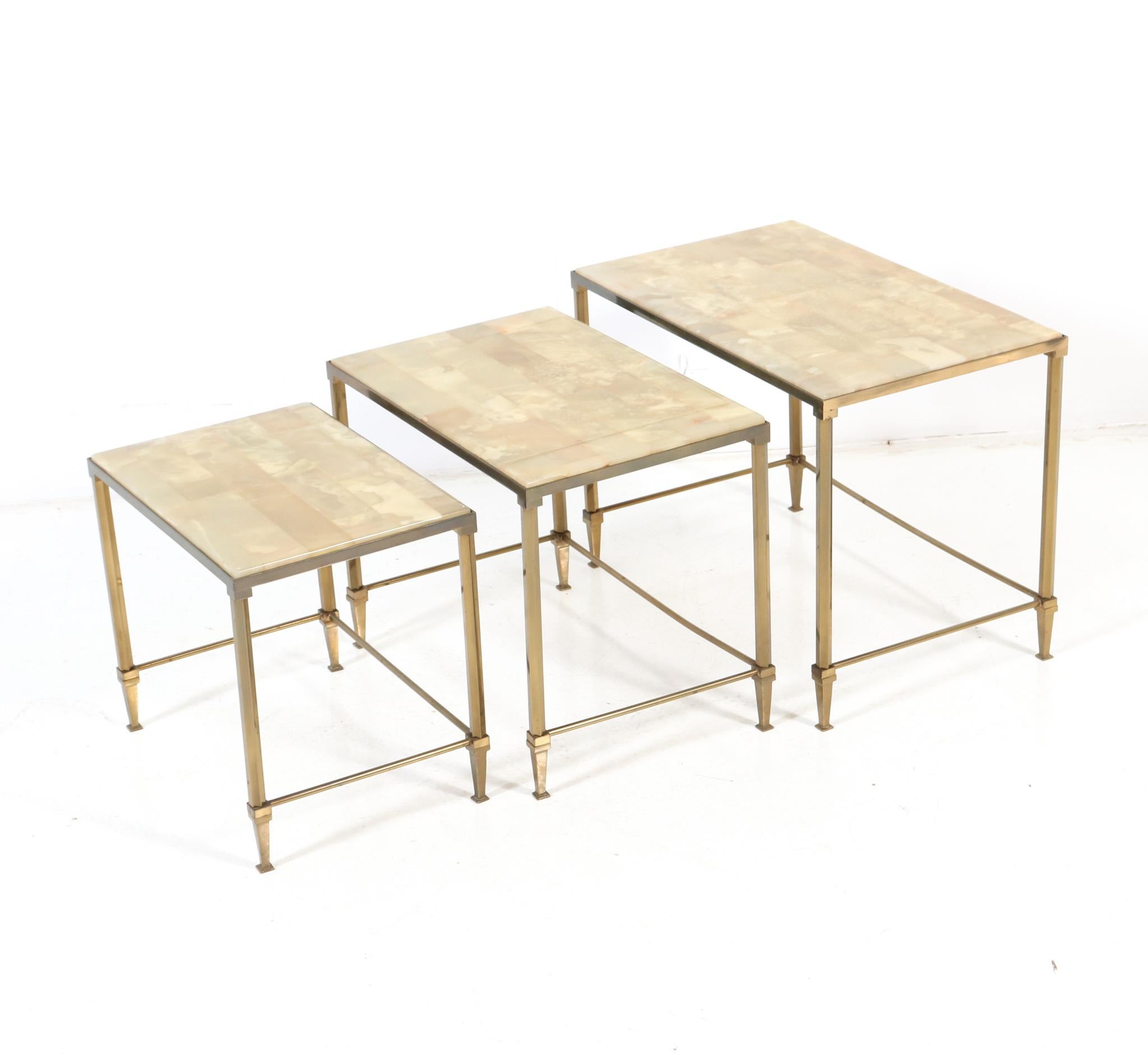 Stunning set of three Hollywood Regency nesting tables.
Striking French design from the 1970s.
Original gilt brass frames with original alabaster tops.
This wonderful set of three Hollywood Regency nesting tables with alabaster tops 
is in very