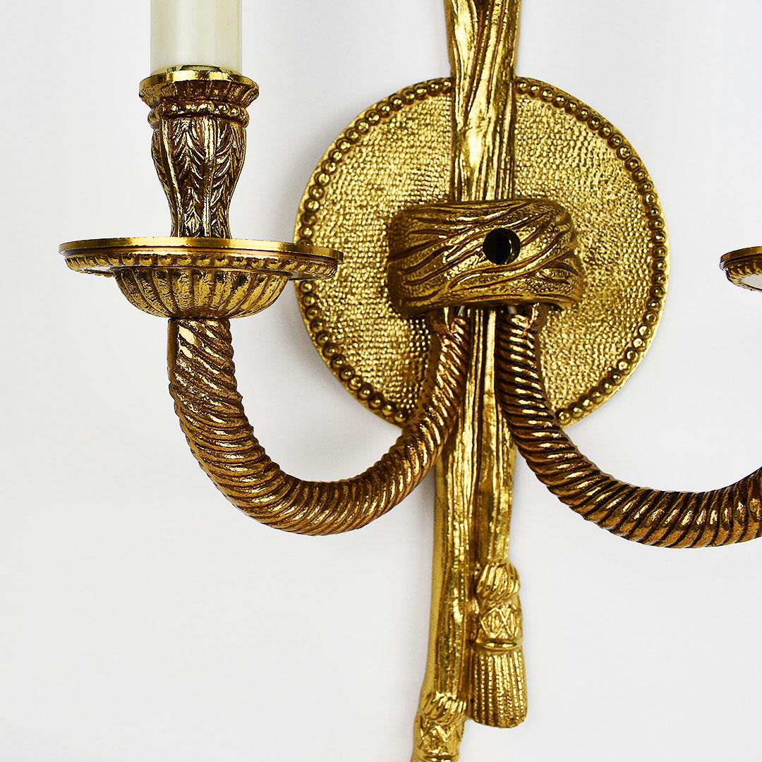 Wired brass sconce with rope and tassel detail. A beautiful two-arm wall light, this piece is a fantastic whimsical piece for any room. This piece affixes to a wall and includes a cord and switch.

9” Wide
15.5” Tall
4.5” Deep
 .