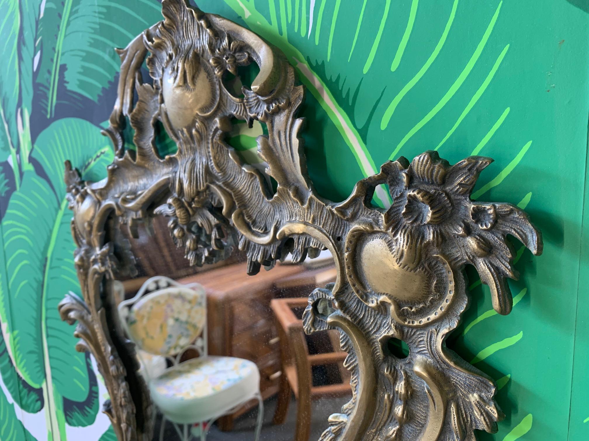 Antique Rococo-style mirror in gilt brass (ormolu). Rocaille-formed frame that makes a statement in any decor. Very good condition with no damage.