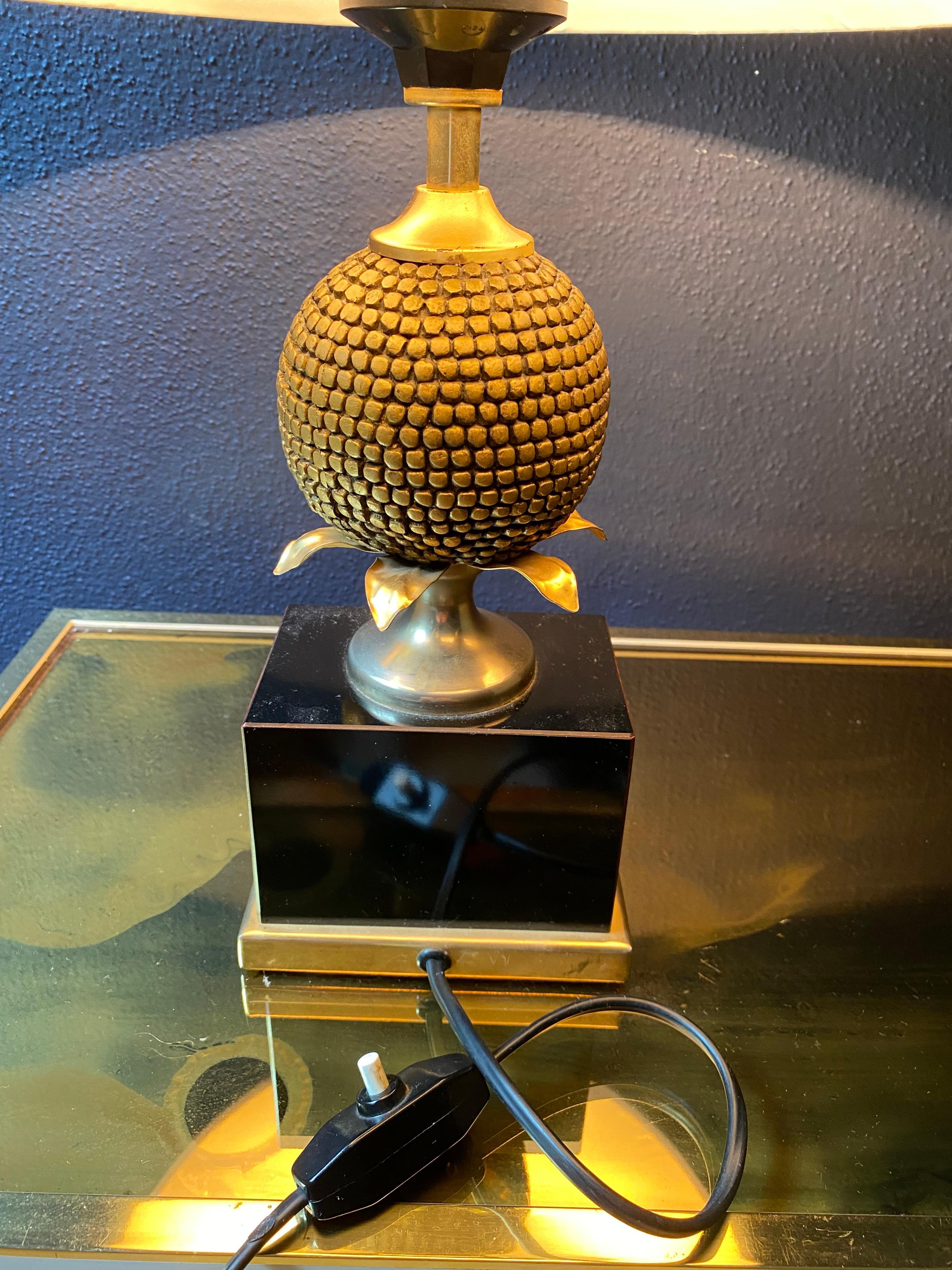 This most exquisite French desk lamp by the renowned Maison Charles hails from the late 1970s and comes with the pictured  cotton shade..

Set on a medium sized black base with a gilt brass frame this lamp the pineapple is somewhat stylized sitting