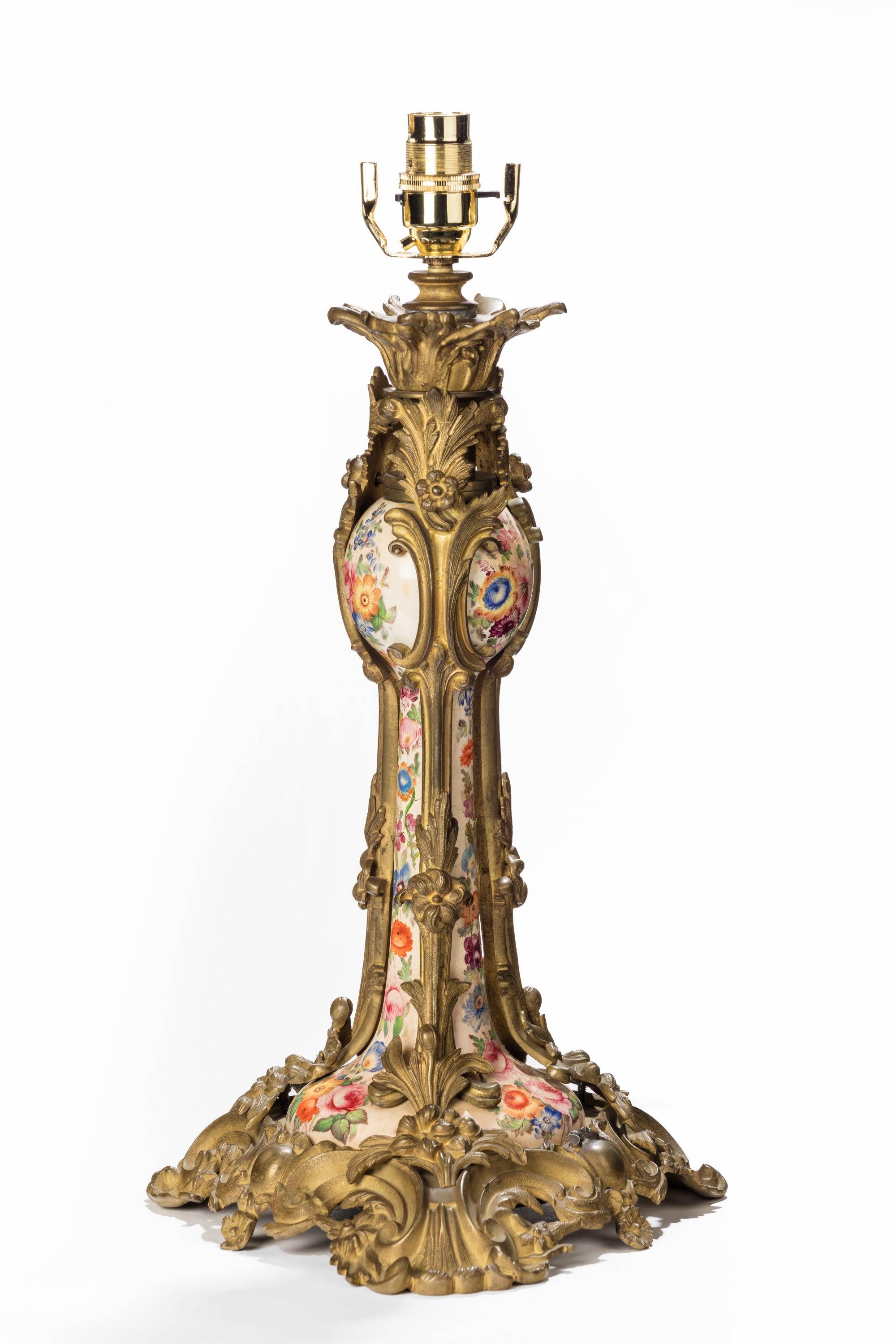 Eine ungewöhnliche Lampe aus vergoldeter Bronze und Porzellan aus dem 19. Jahrhundert in Rokokoform. Ein fein bemaltes Mittelstück aus Porzellan mit Restaurierungen. Von höchst kunstvoller Form und ungewöhnlich in Stil und Qualität. Ursprünglich ein