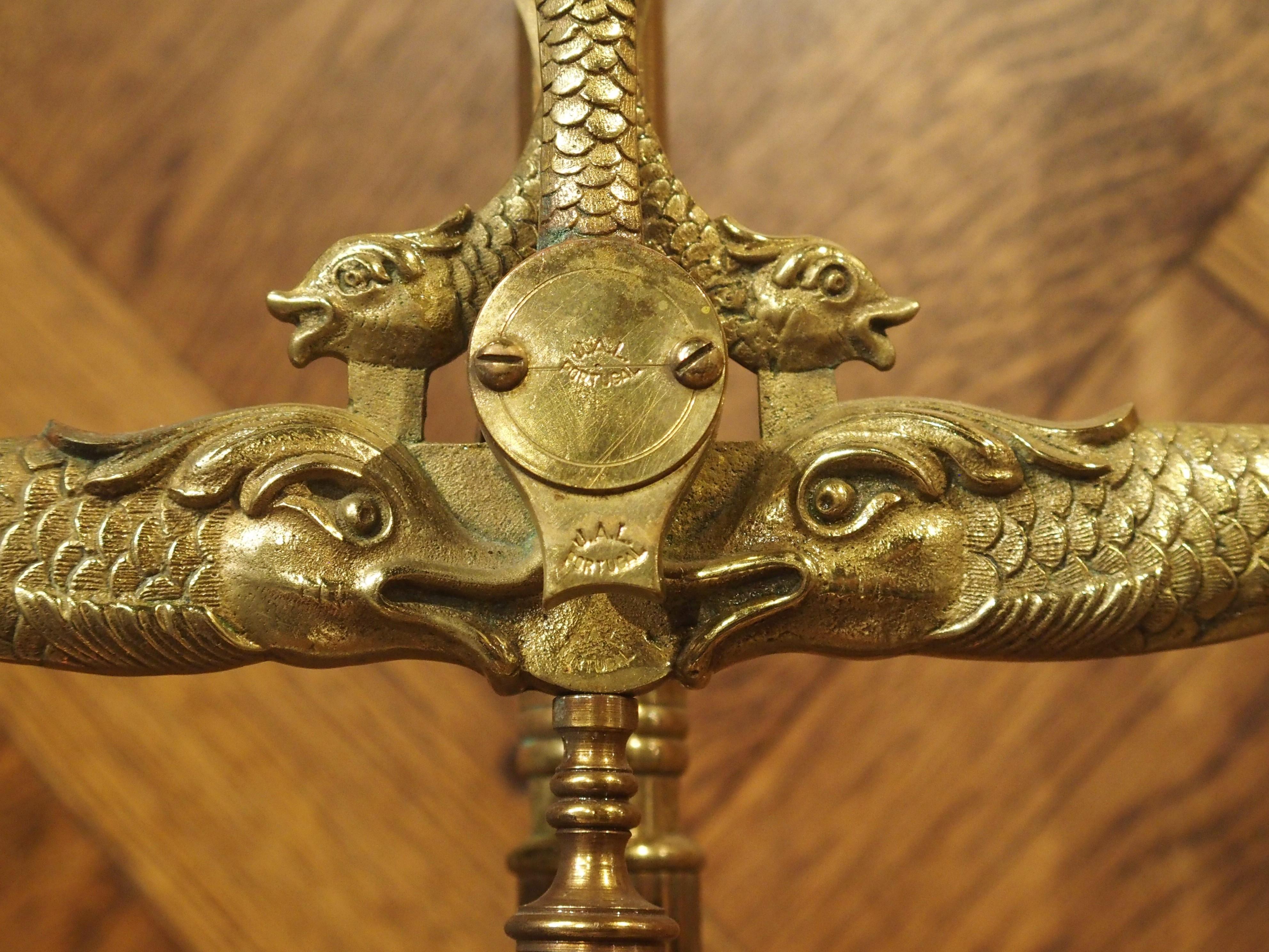 Embellished with stylized dolphins and serpents, this gilt bronze and brass apothecary scale was made in Portugal in the early 1900s.

This style of scale is called a “pivot balance” because the beam, which is the horizontal lever, is pivoted to