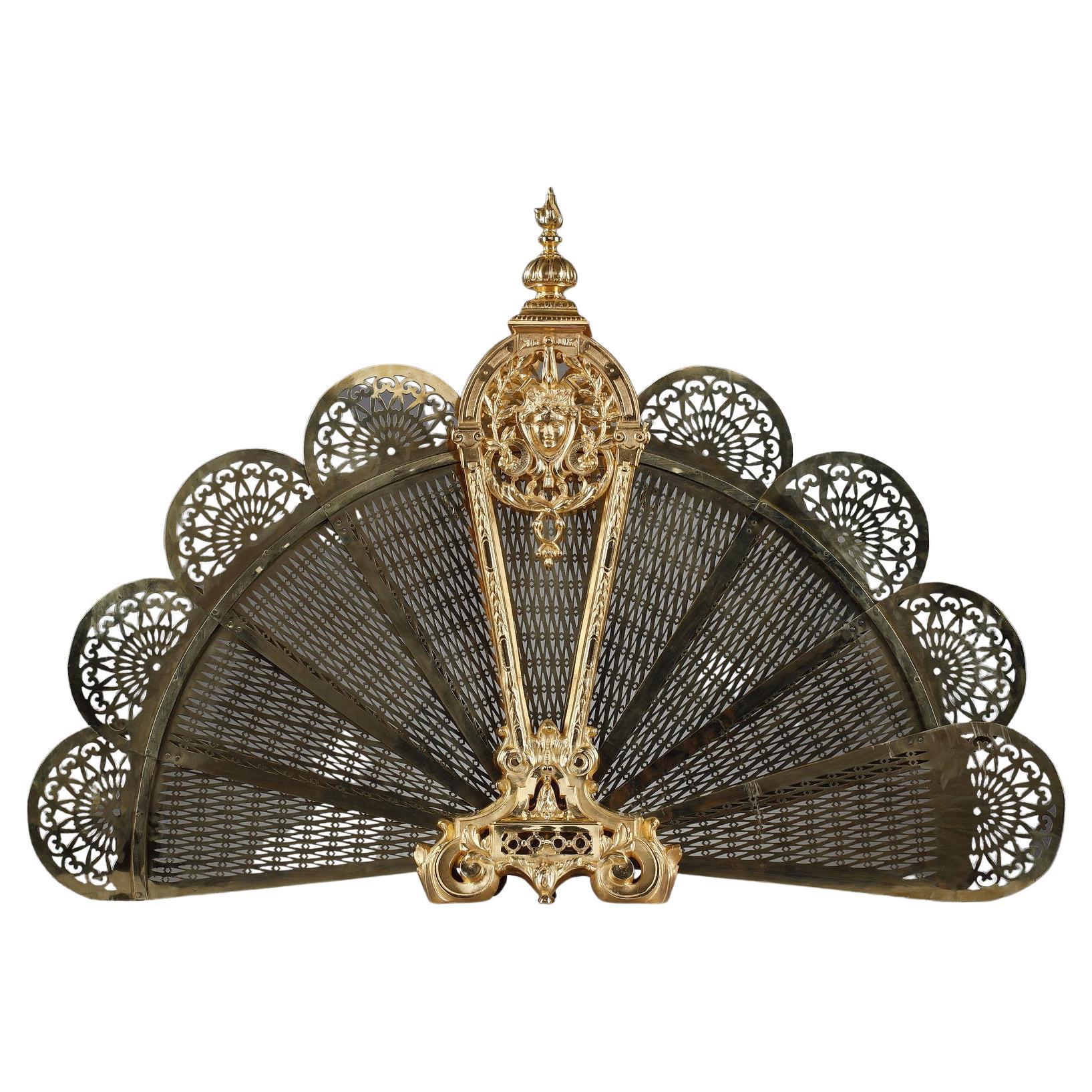 Gilt bronze and chased fan-shaped fire screen with female face decoration