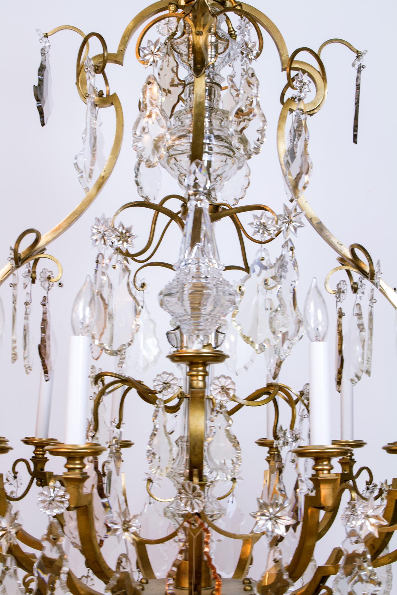 Louis XV style chandelier with original aged gilt bronze finish. 12 Lights, with crystal stem pieces. Clear, smoky, and rose colored pendalogue crystals with rosettes. 
UL Listed

Dimensions: 
Height: 59
