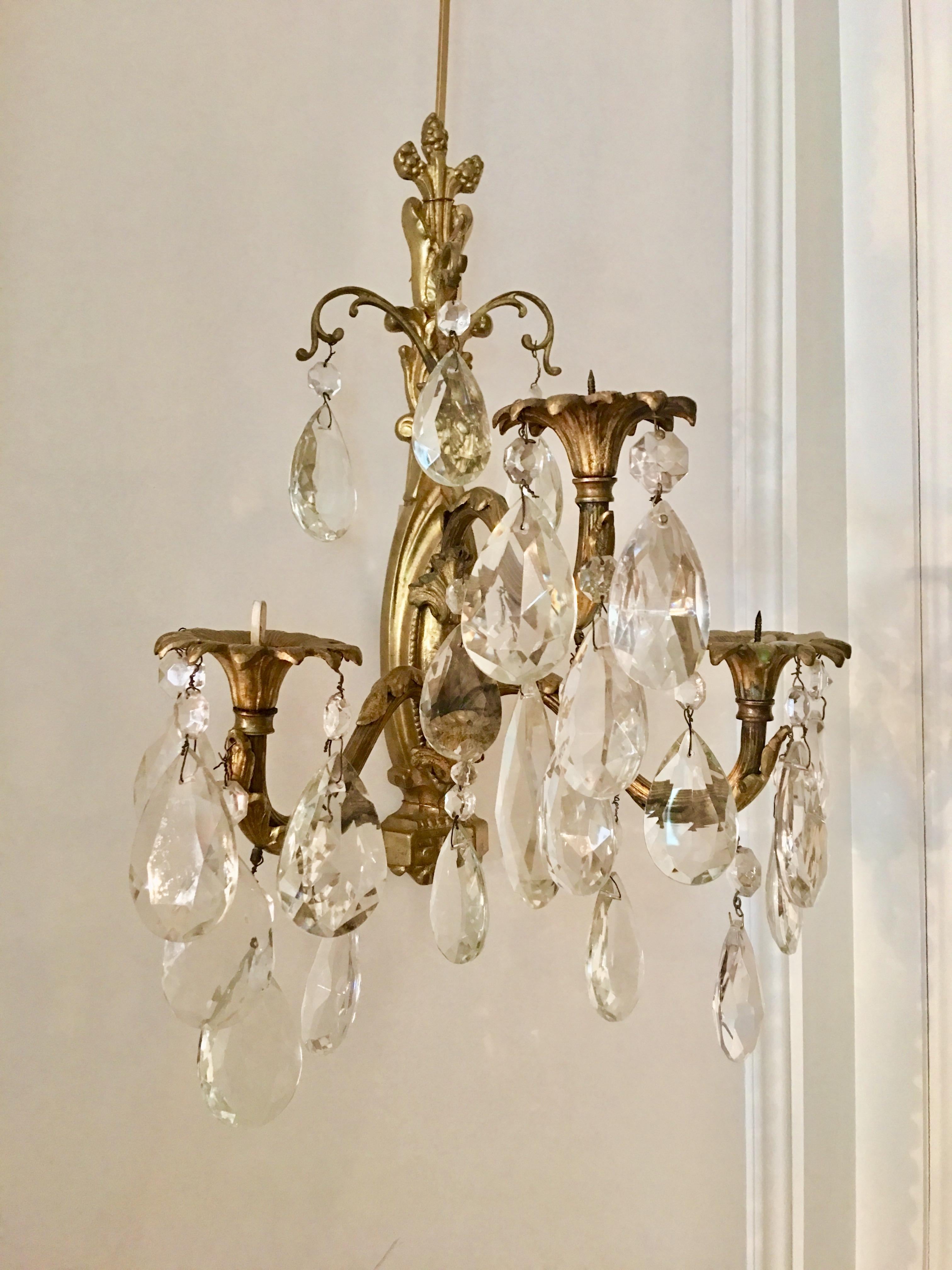 Delightful pair of 3-branch Louis XV style gilt bronze and crystal pendant wall sconces. Each candle arm features candle holders (bobèches) in the form of a blooming flower. Candelight is gently reflected by hanging crystals. Non-electrified.