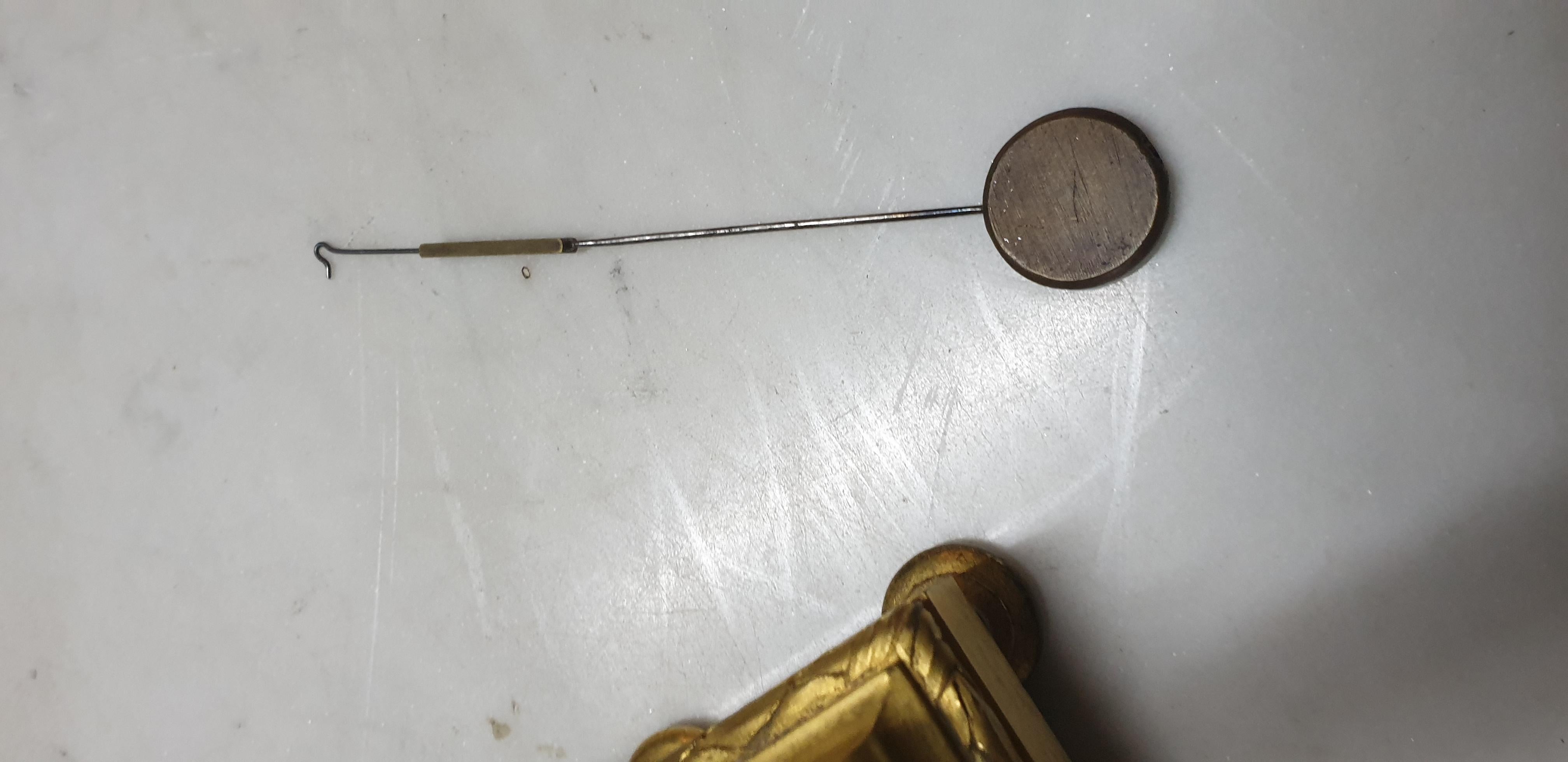 Uhr aus vergoldeter Bronze auf 2 Ziegenfüßen, verziert mit Lorbeerblättern und bekrönt von einem Feuertopf; Einlagen aus blauer Emailpastille, mit Kleeblatt.

Das Zifferblatt gibt einen Einblick in die Mechanik, der Rand ist aus weißem Porzellan