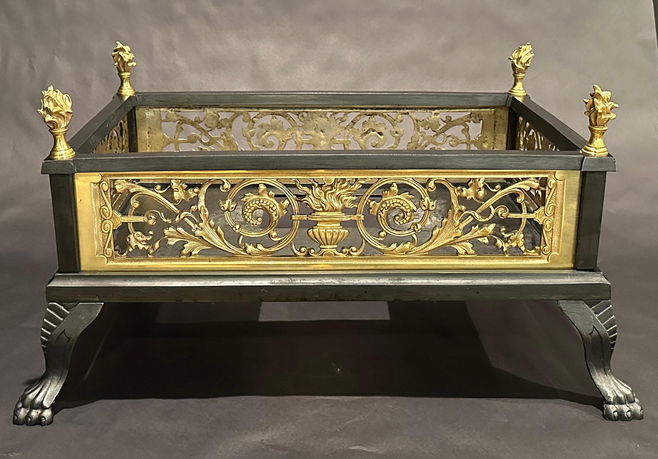 19th century highly decorative gilt bronze and iron box form fireplace grate insert. In the Louis XVI style with urn and flame center flanked by scrolling florets and flame form finials at top of each corner. Removable bottom insert.