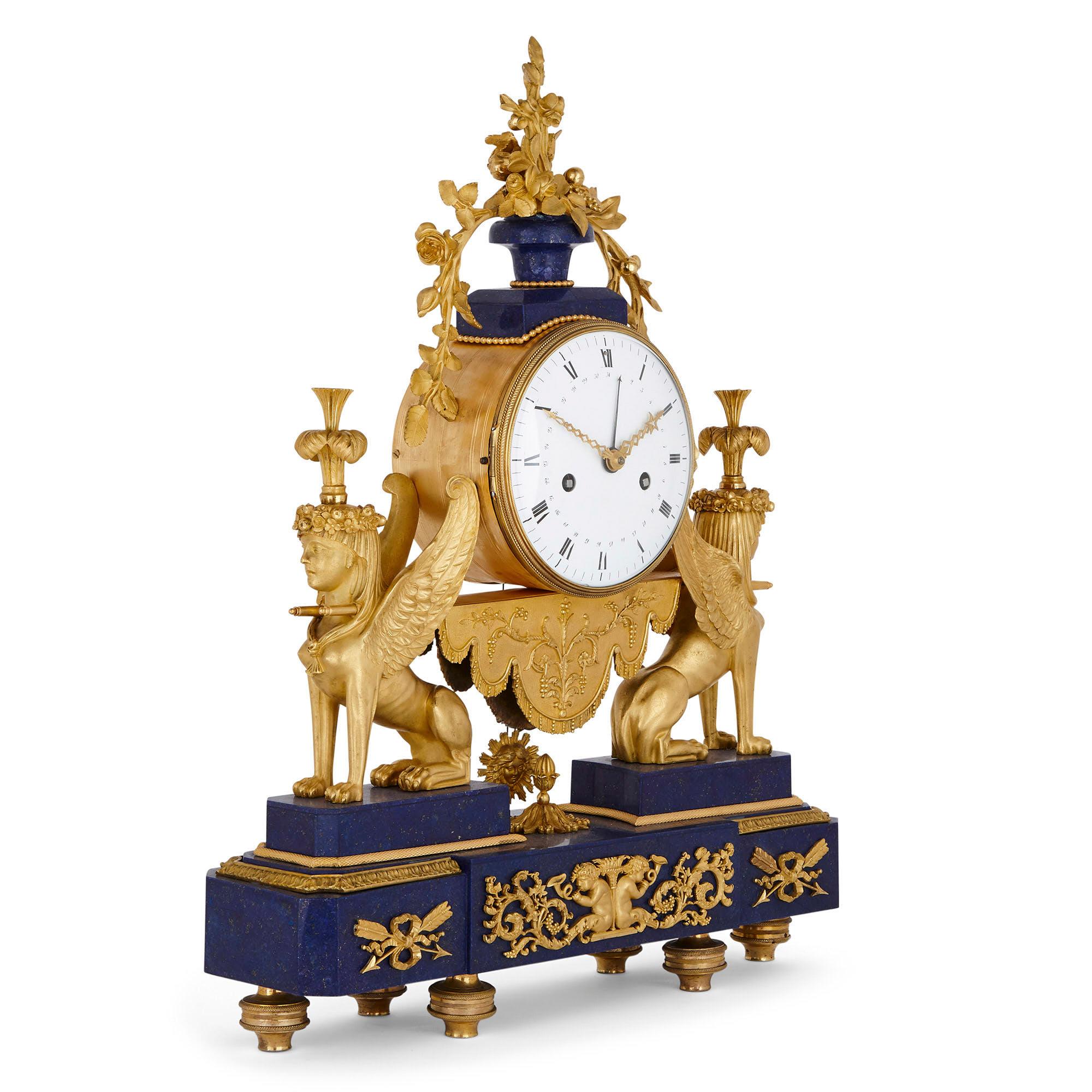Cette exquise horloge de cheminée du début du XIXe siècle est montée en bronze doré et a bénéficié de l'ajout d'un placage de lapis-lazuli plus tardif. L'horloge est formée d'un tambour cylindrique inséré dans un cadran circulaire inscrit en