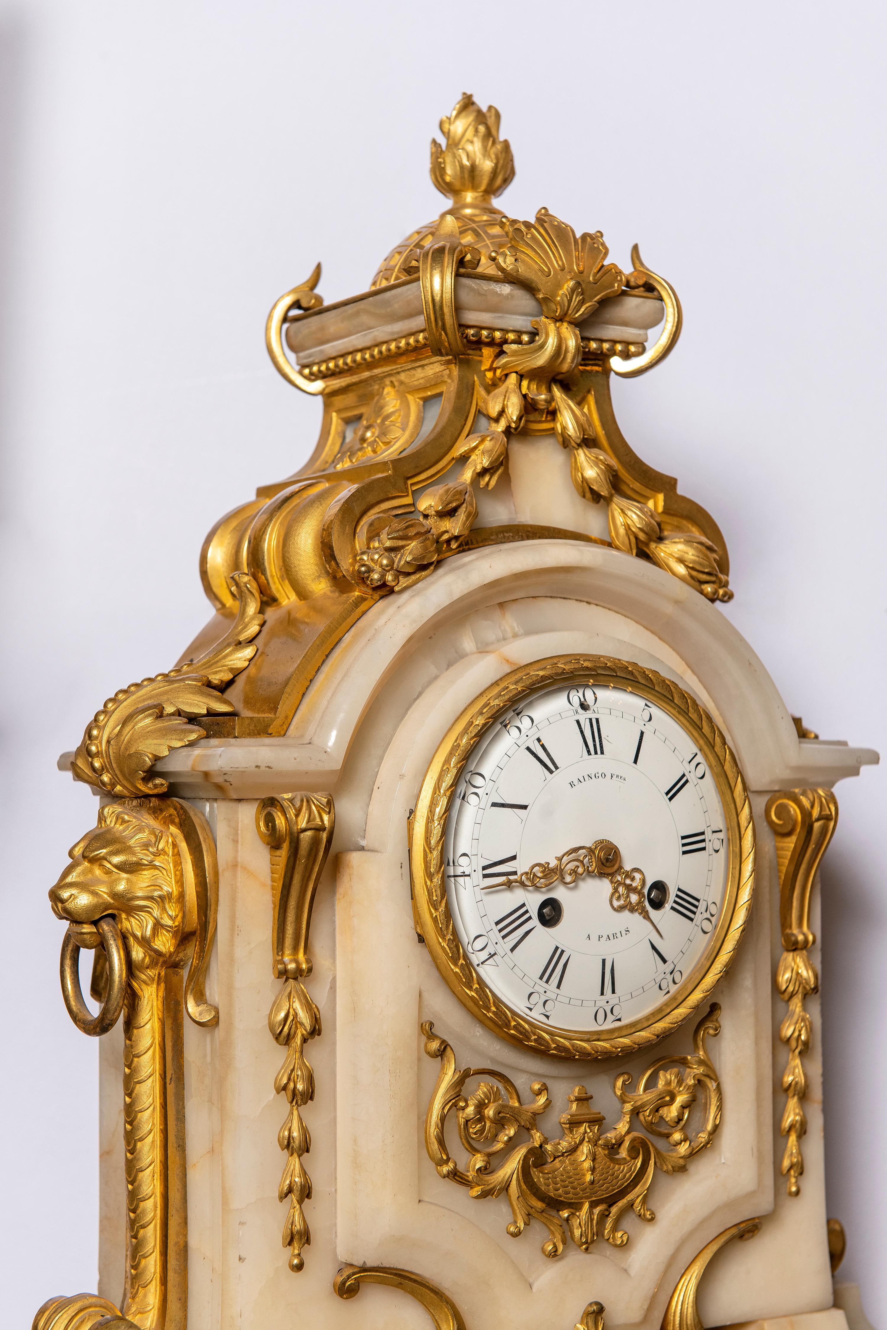 Garniture d'horloge à trois pièces en bronze doré et marbre. Horloge signée Raingo Fres. France, 19ème siècle.
L'horloge fonctionne.

Dimensions de l'horloge : 71 cm de hauteur, 46 cm de largeur, 22 cm de profondeur.
Dimensions des candélabres :