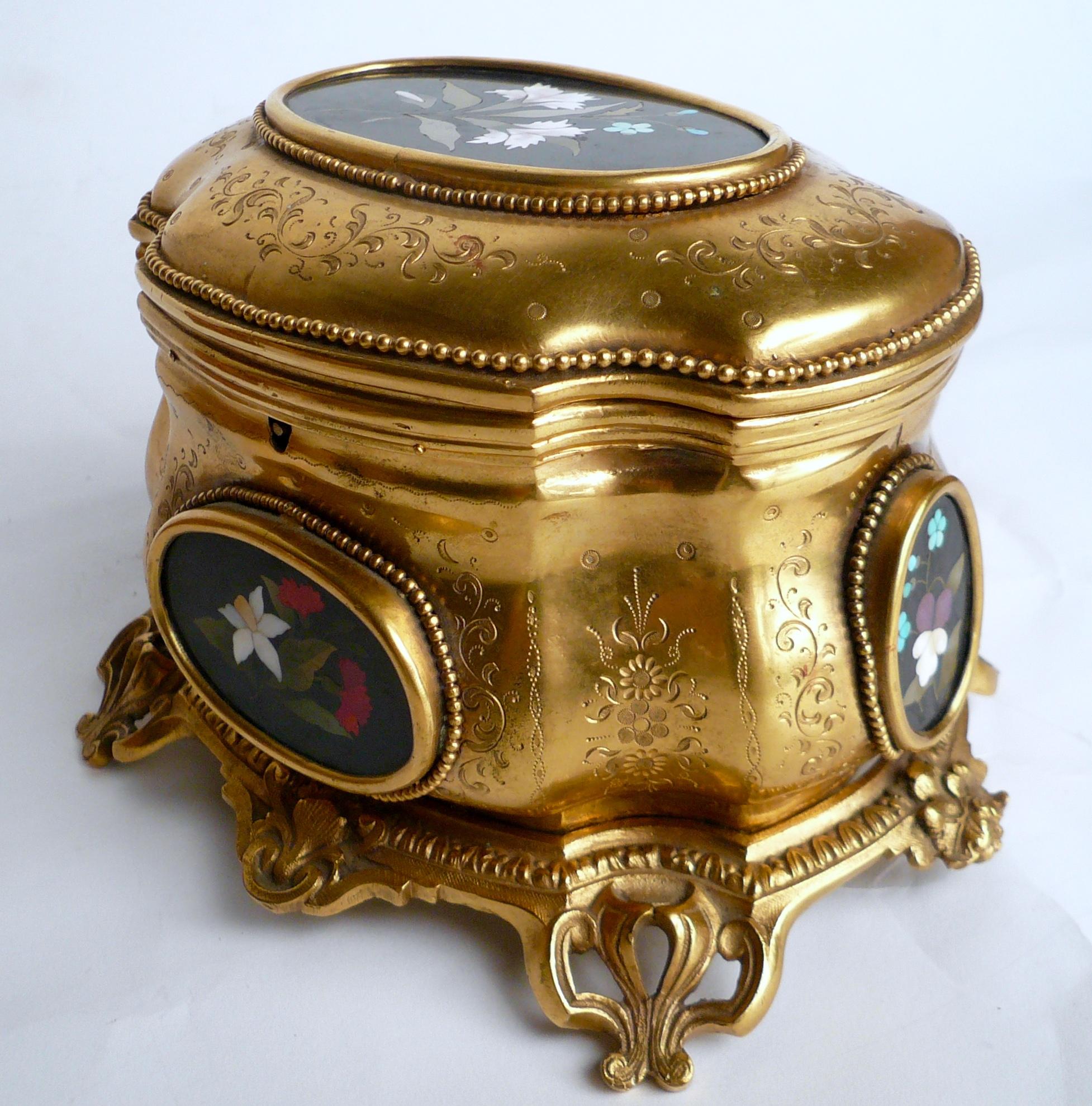 This hand chased gilt bronze box features four oval inlay stone floral reserves that include forget-me-nots, and carnations.
It is signed by renowned maker Tahan of Paris.