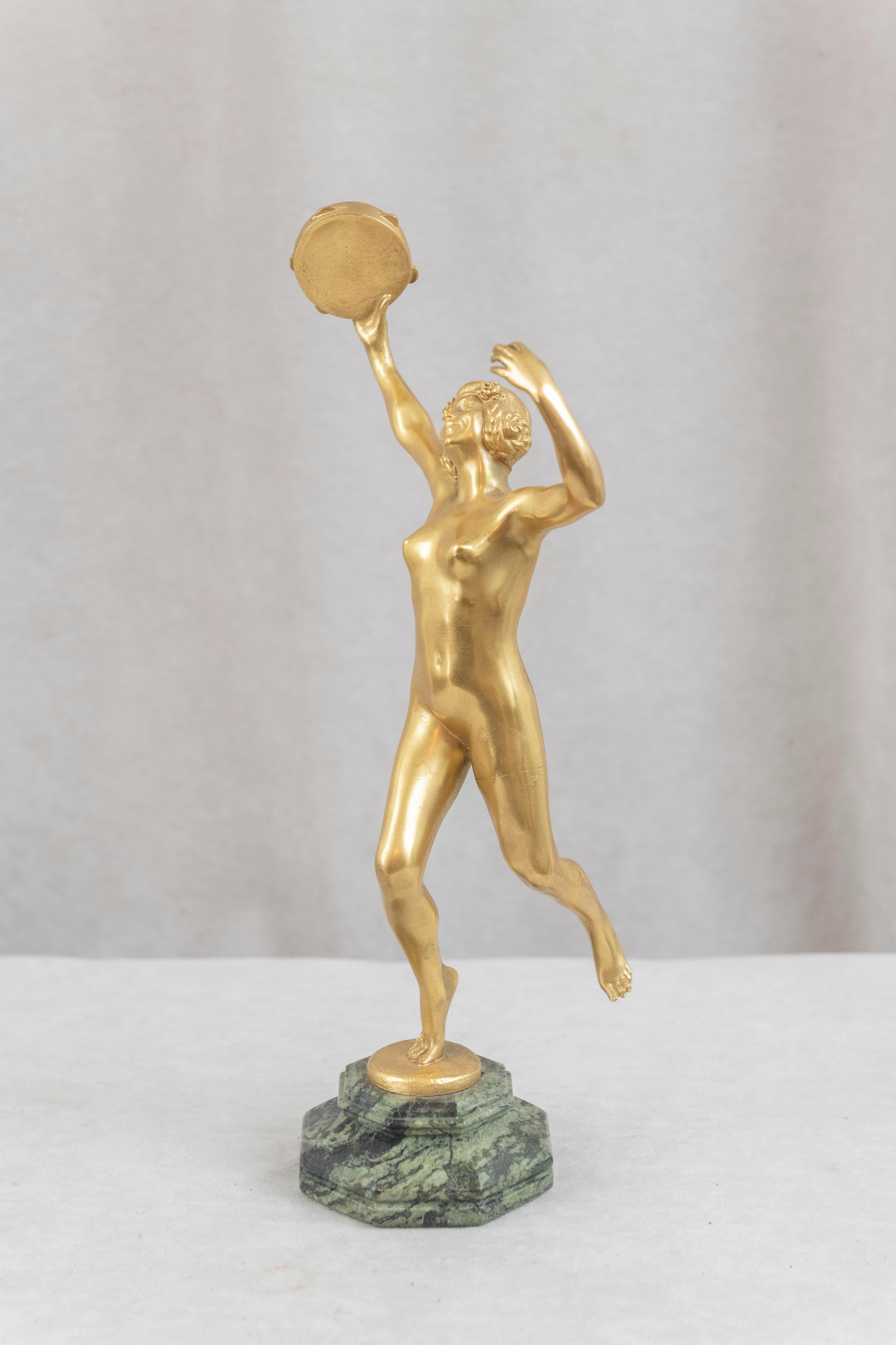 A graceful gilt bronze period Art Deco figure of a nude young lady holding a tambourine as she dances. Mounted on a colorful marble base and signed by the noted French artist Eugène Désiré Piron (1875-1928). The signature was abbreviated to just E.