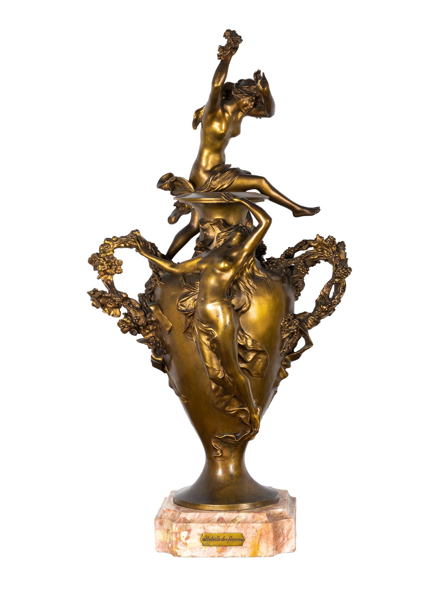 Félix Charpentier's masterpiece, 'Bataille des fleurs,' is a stunning golden bronze statue with a beautiful gilded patina finish. It draws inspiration from the colorful Carnival festivities of Côte d'Azur and portrays two nude nymphs and putto who