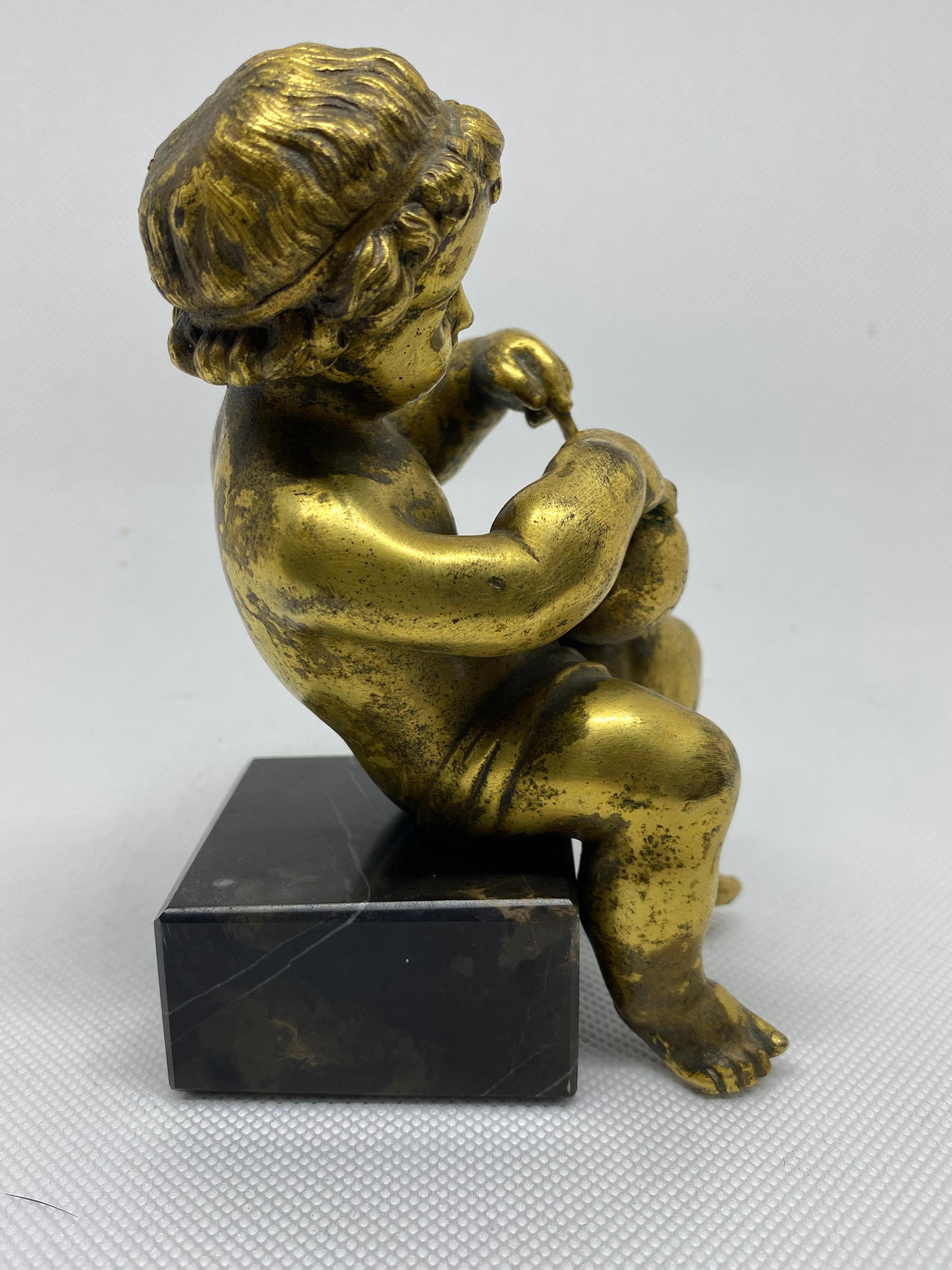 This charming depiction of a boy measuring the earth with a compass is an allegorical sculpture of geography. This bronze was cast using the lost wax technique and is fire gilded. He sits, but is not affixed, on a modern marble base. This sculpture