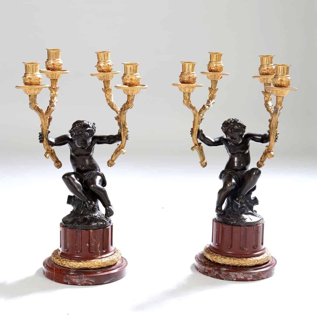 Garniture de pendule du XIXe siècle, la pendule avec un chérubin en bronze finement moulé et patiné assis sur une colonne en marbre rouge avec des montures en bronze doré, il porte le mouvement de la pendule dans une guirlande de fleurs dorées, le