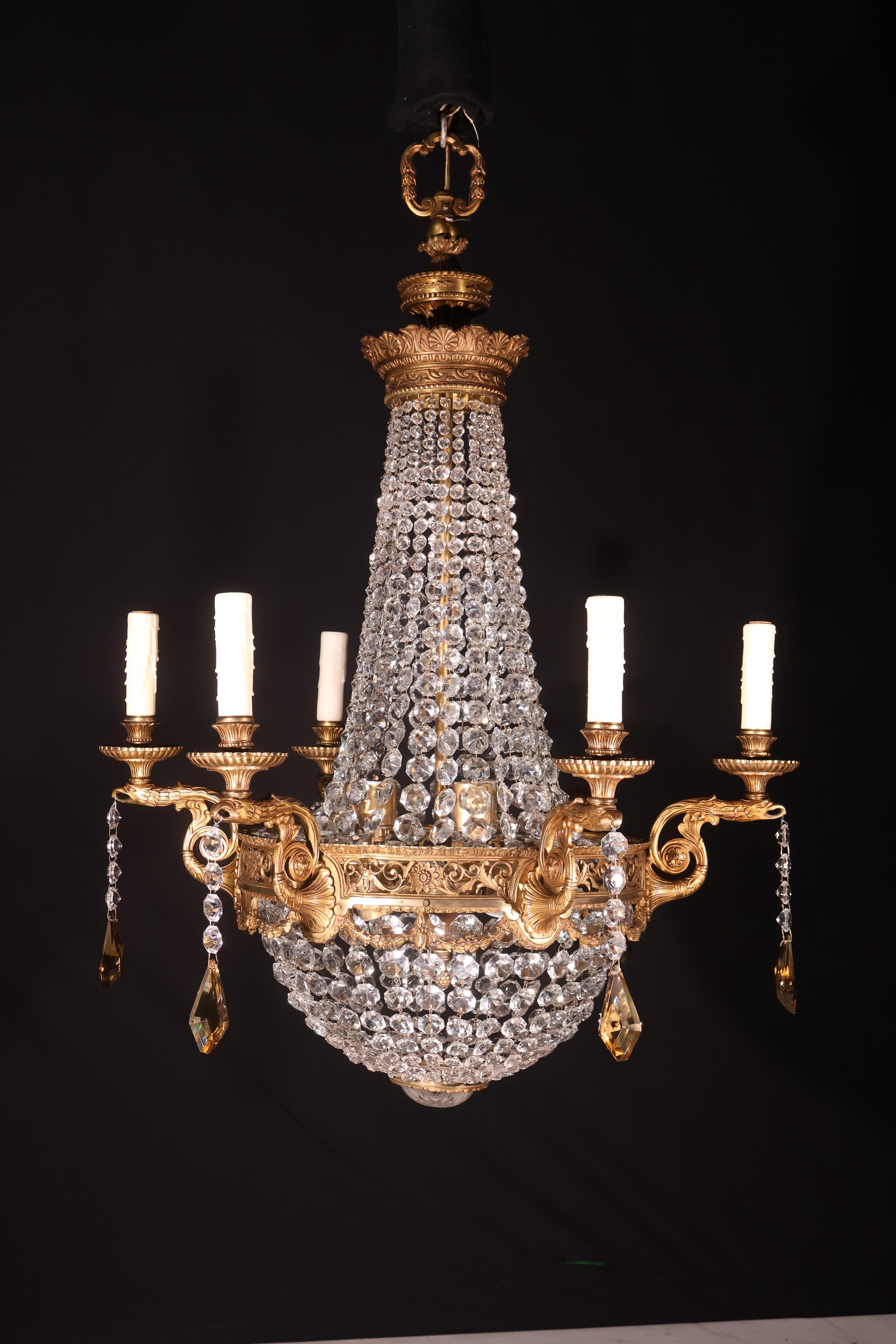 Raffinato e decorativo lampadario in bronzo dorato e cristallo in stile Luigi XVI con teste di aquila. 12 luci. Francia, circa 1920.
Dimensioni: Altezza 38  Diametro  26