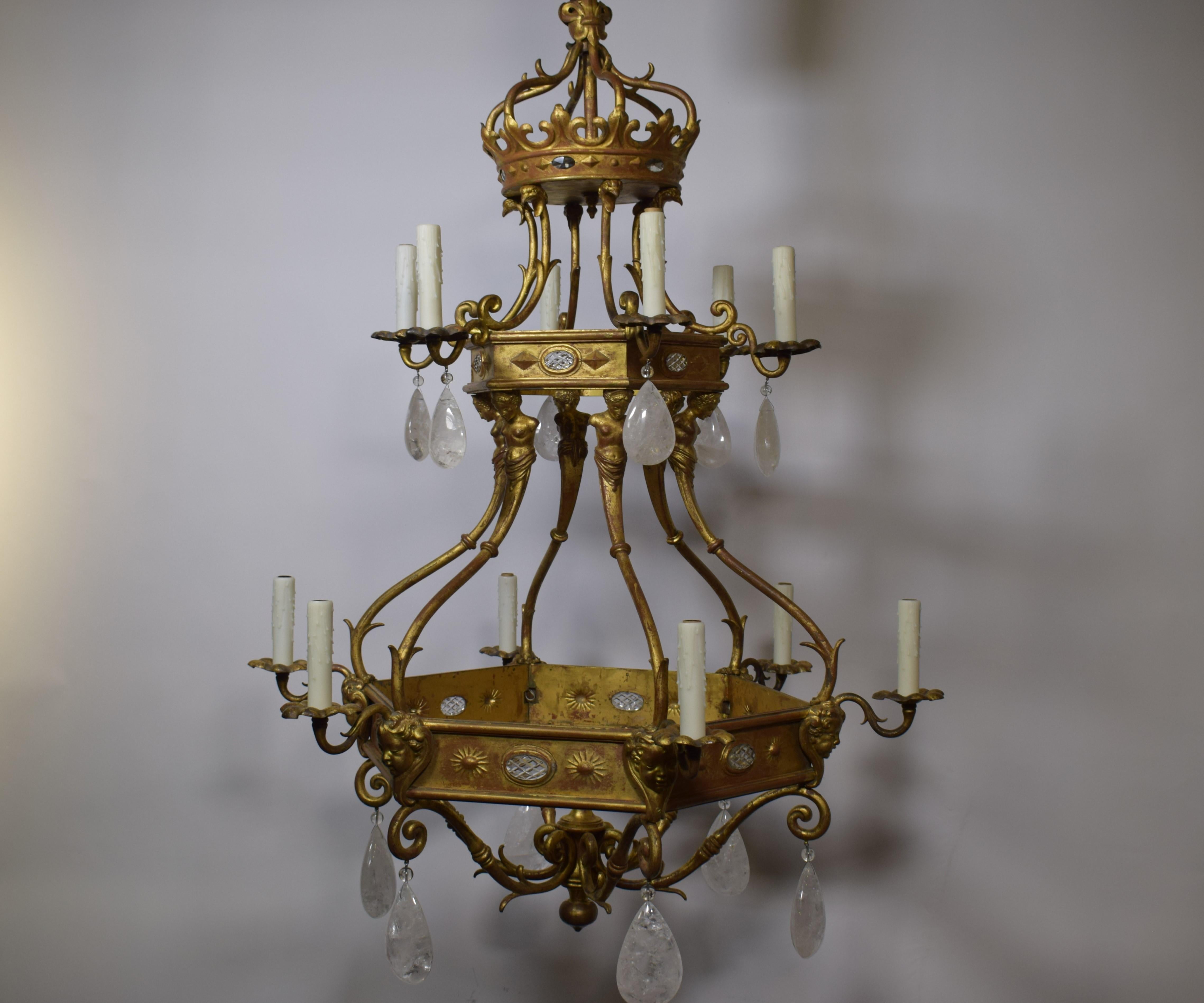 A very fine and unusual gilt bronze chandelier with rock crystal pendalogues. Two hexagons featuring oval crystal reserves issuing six arms each in a row on two levels. Stylized crown top.
France, circa 1900
Dimensions: Height 51