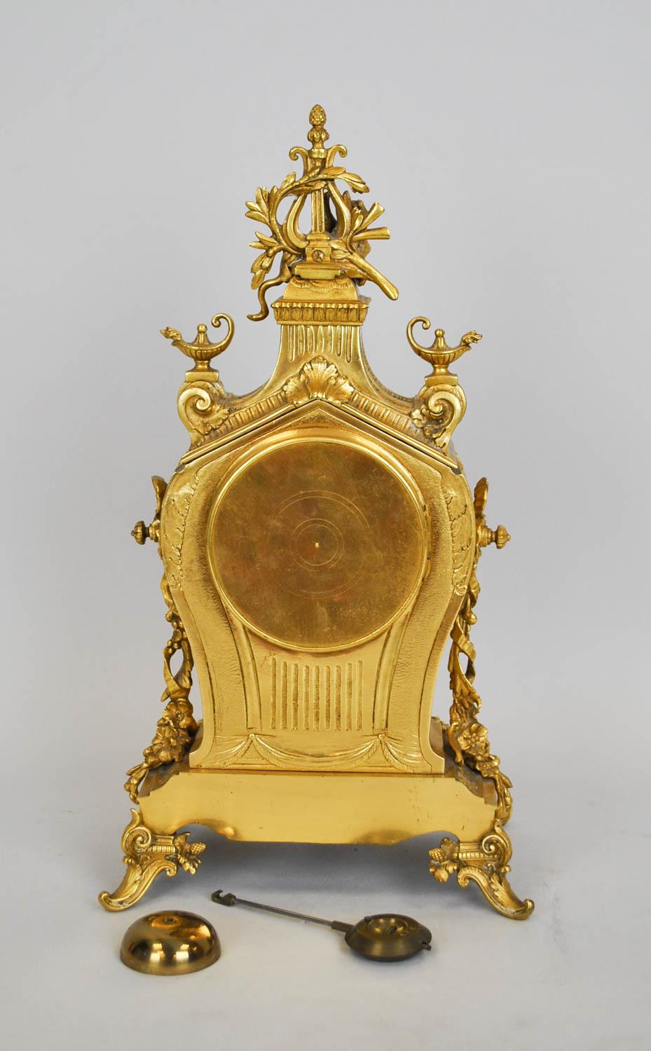 Encantador reloj de bronce dorado, ricamente decorado: está coronado por una esfinge y una lira, una boca de león abierta sobre la esfera, guirnaldas de flores y lámparas de aceite.   

La esfera de porcelana está decorada con guirnaldas de flores;