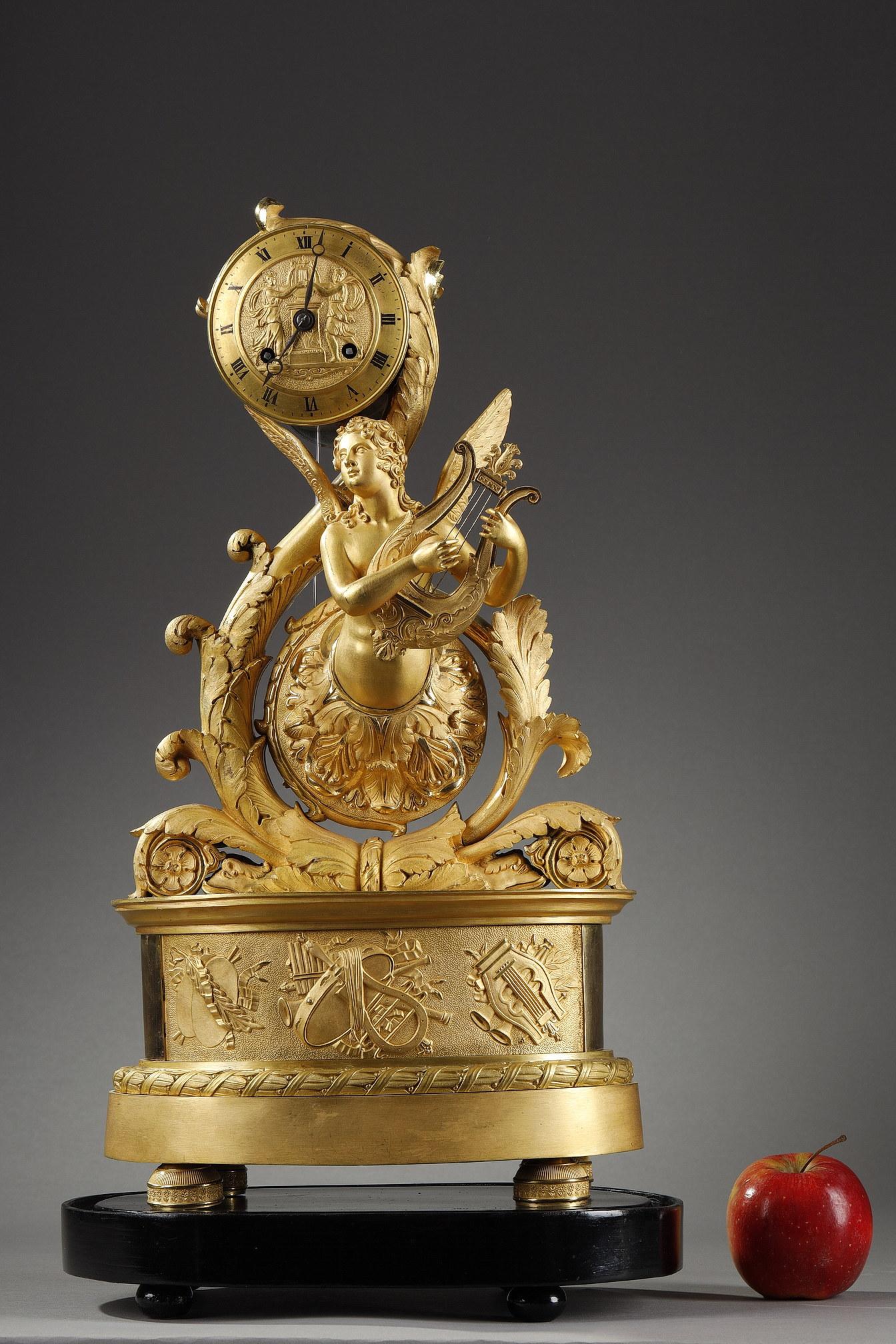 A Charles X period ormolu clock representing a winged genie playing the lyre in acanthus leaves populated by dolphins. The dial, decorated with two nymphs carrying a lyre on an altar, indicates the hours in black Roman numerals. The oval base is
