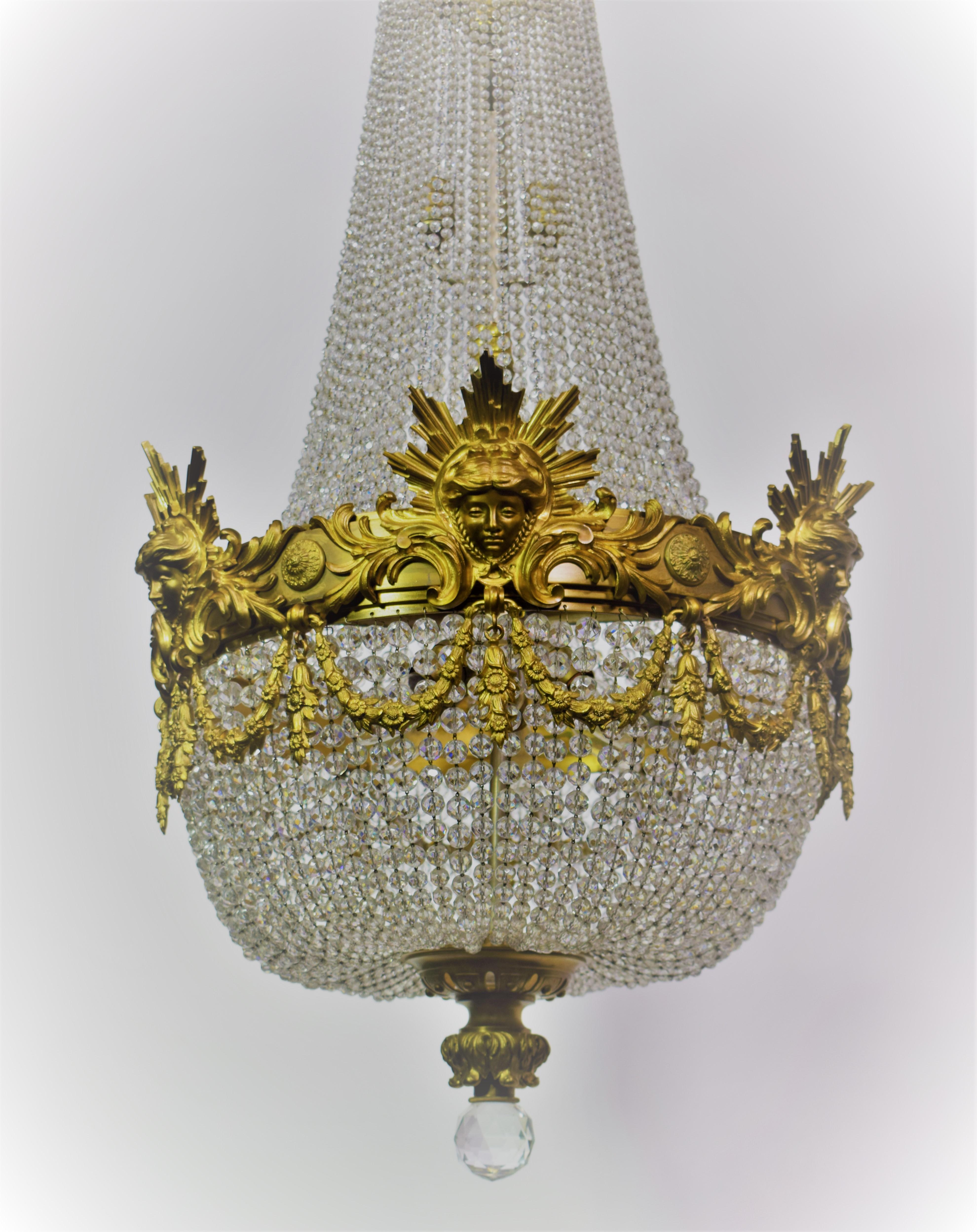 A fine gilt bronze and crystal basket style chandelier by Baccarat. Main ring featuring Sunburst masks of Apollo. Highly important crown. Pierced bottom finial featuring handcut ball. France, circa 1900. Fourteen lights (Six in the
