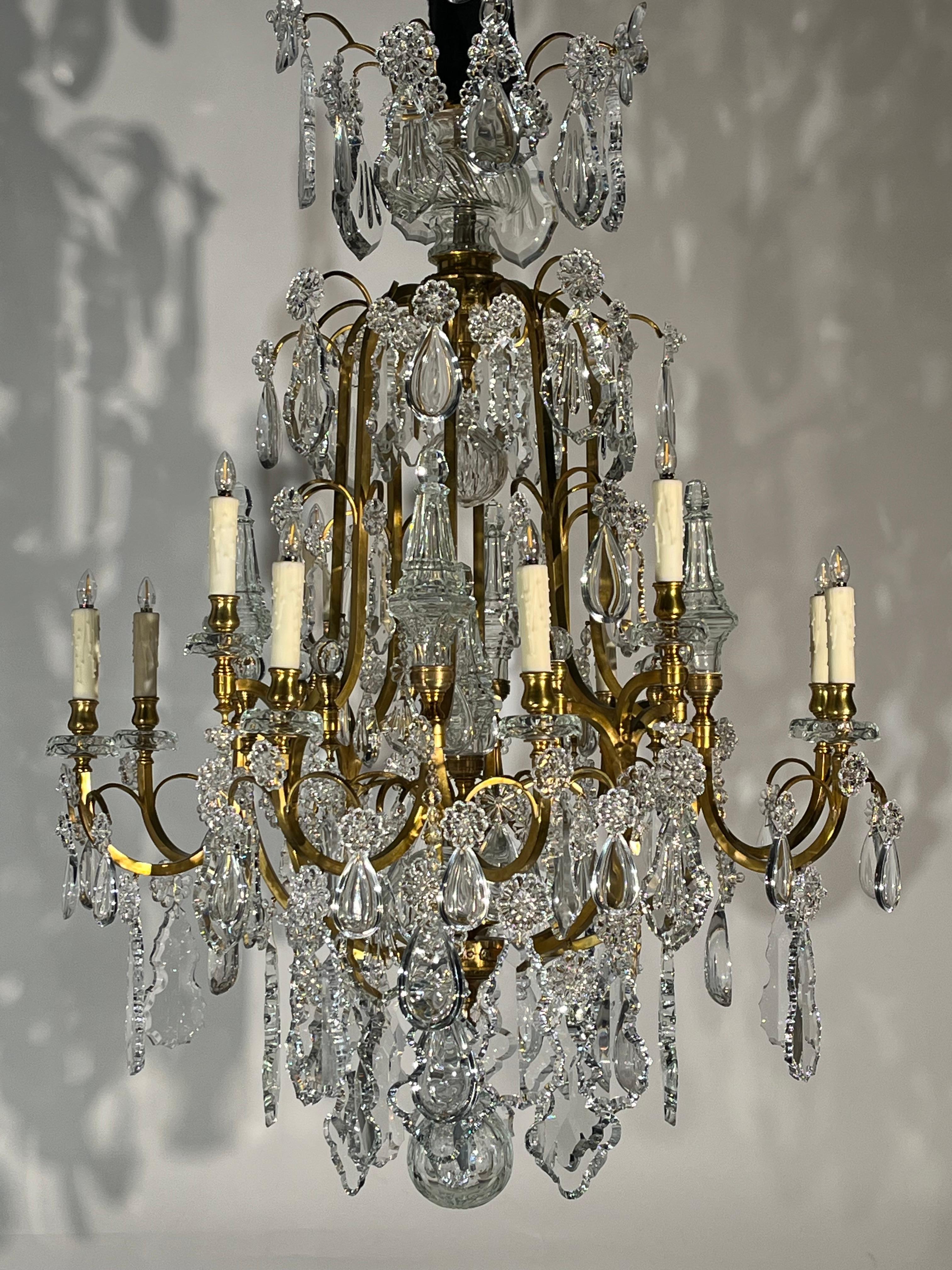 Un raffinato lampadario a gabbia in bronzo dorato e cristallo di gusto Luigi XV.
Francia, circa 1920. 12 luci. 
Dimensioni: Altezza 54