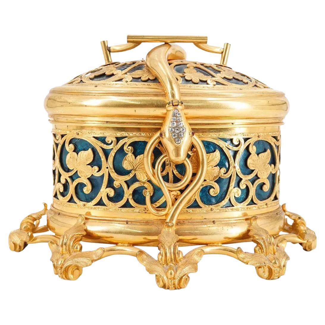 Our truly extraordinary jewelry chest from Tahan of Paris, circa 1900, features a gilt bronze frame and lid with floral vine openwork revealing green colored glass inserts, and snake form handle decorated with clear and ruby colored faceted glass,