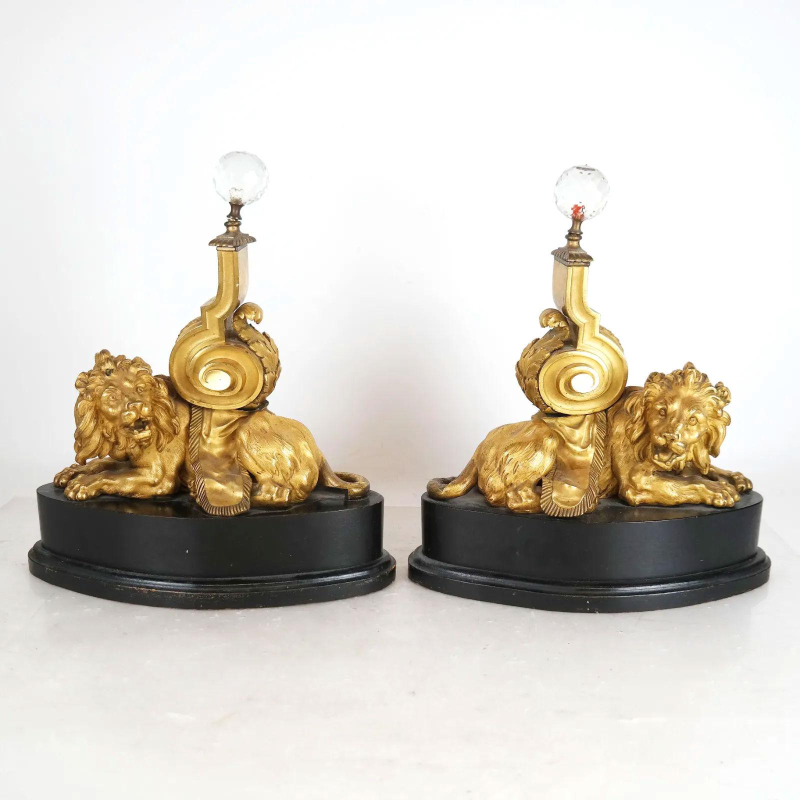 Our pair of nineteenth century ormolu bronze chenets were later mounted on ebonized wooden plinths for use at table lamps, currently with later spherical shaped crystal finials Sockets and wiring may be added for an additional fee.
