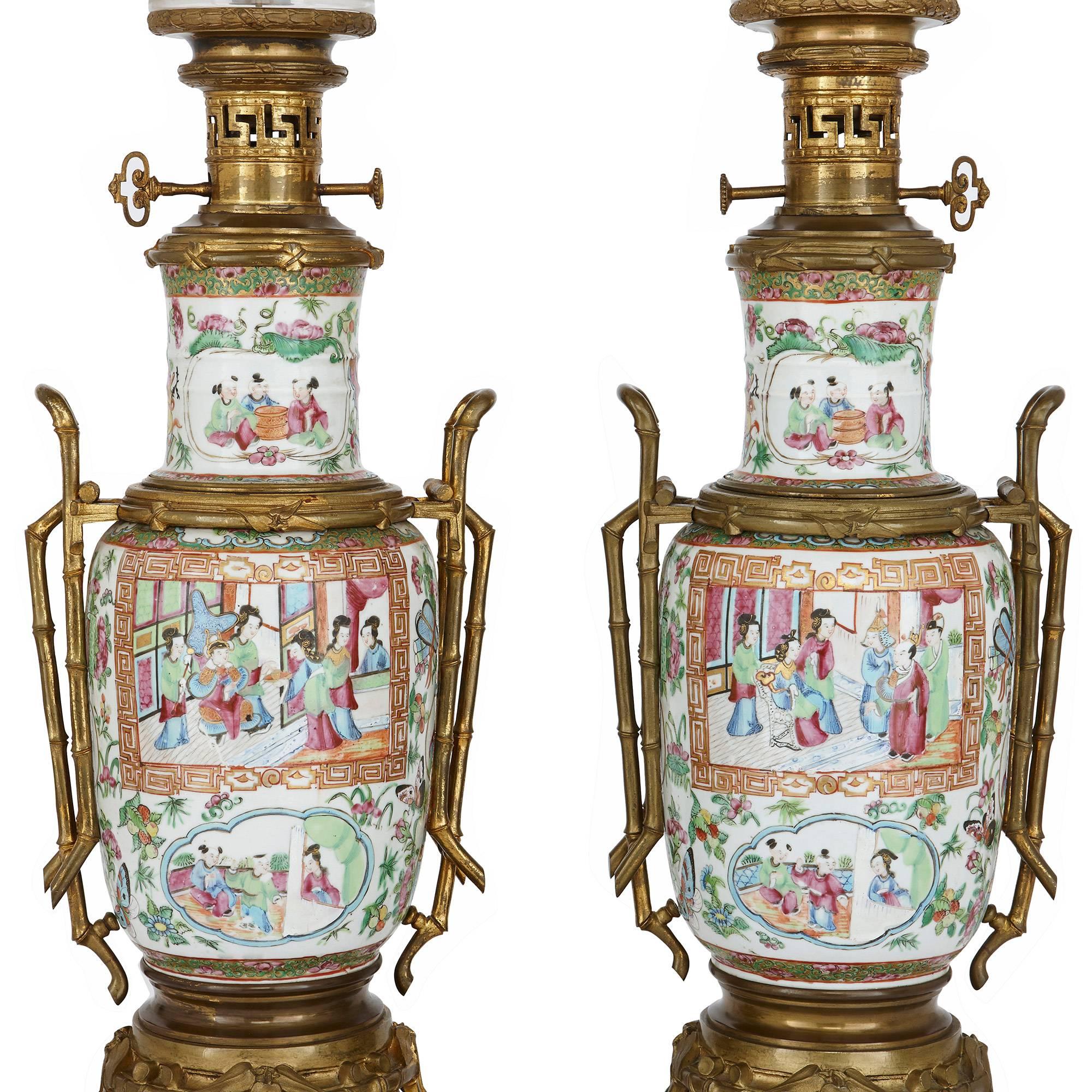 These elegant lamps are crafted from Chinese Canton famille rose porcelain and mounted with French gilt bronze (ormolu). The lamps feature beautiful vase-form porcelain bodies, which are finely painted with Chinese court scenes, as well as flowers,