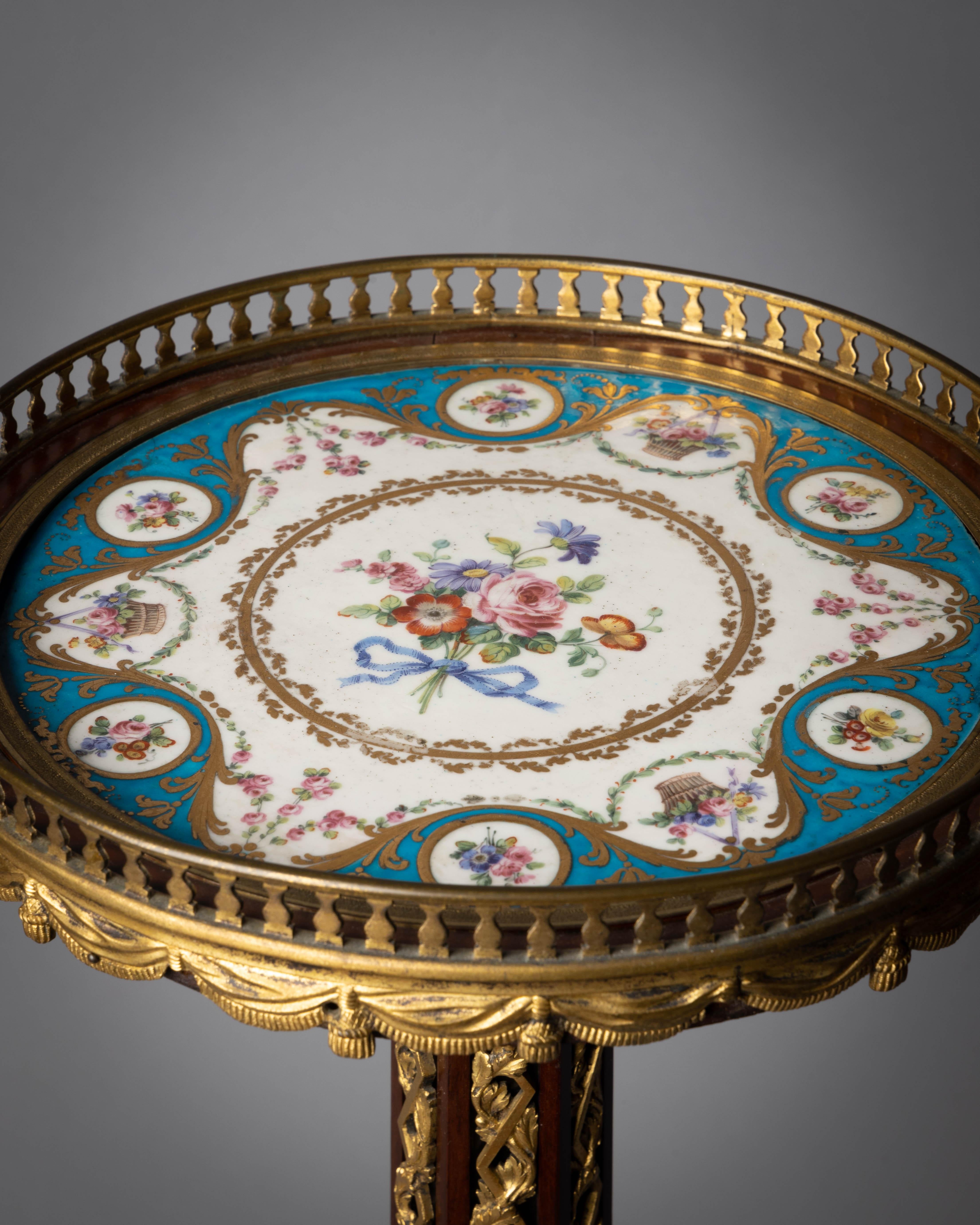 The hexagonal center support with applied and inset ormolu grape and vine guilloche raised on three gilt bronze mounted mahogany legs with acanthus leaves and segmented by gilt bronze paterae appliques, the cabriole legs with gilt bronze sabots.