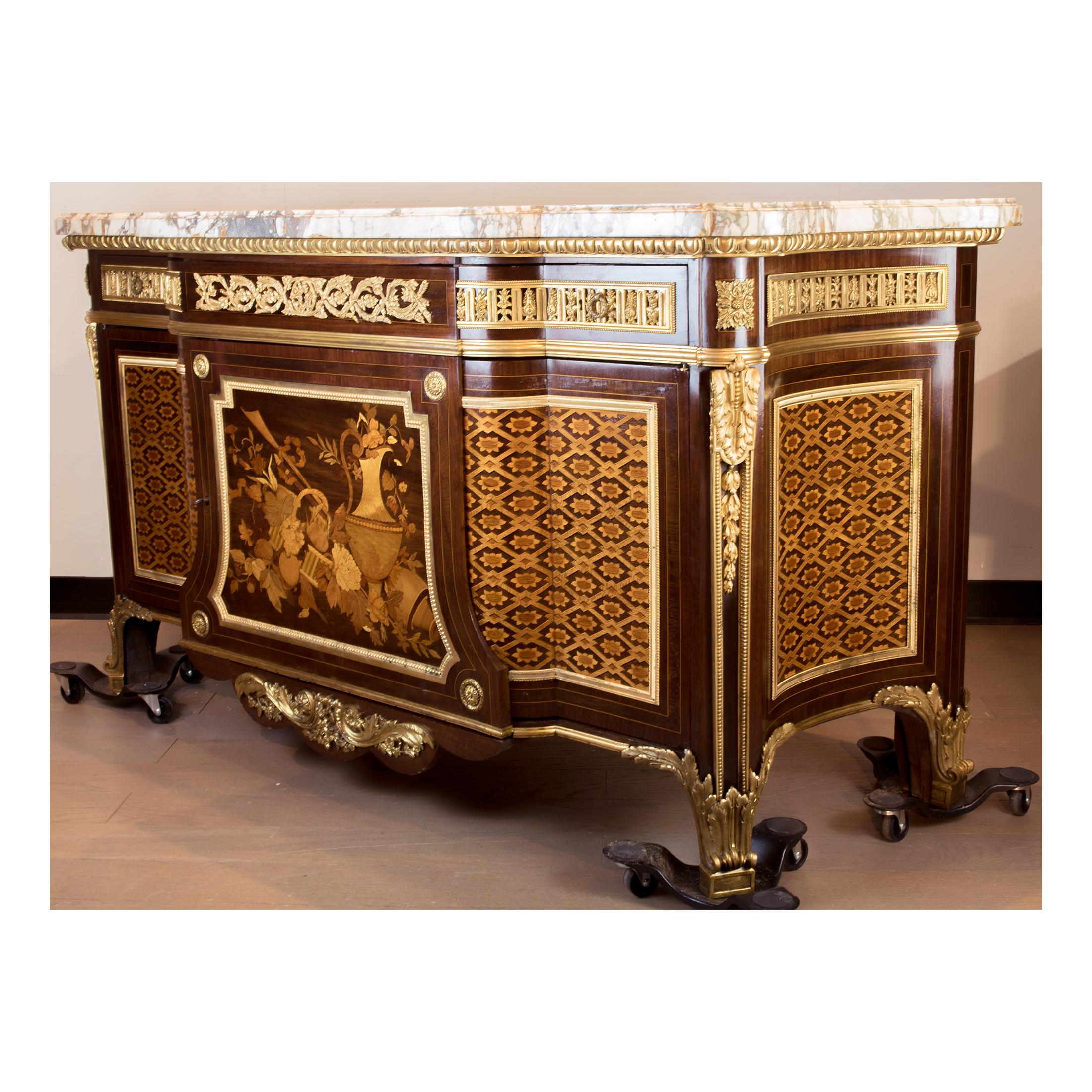 A French ormolu-mounted mahogany, amaranth, sycamore and fruitwood marquetry and parquetry commode after the model by Jean Henri Riesener.

The brècheviolette marble top above a breakfront frieze with three drawers over two cupboard doors opening