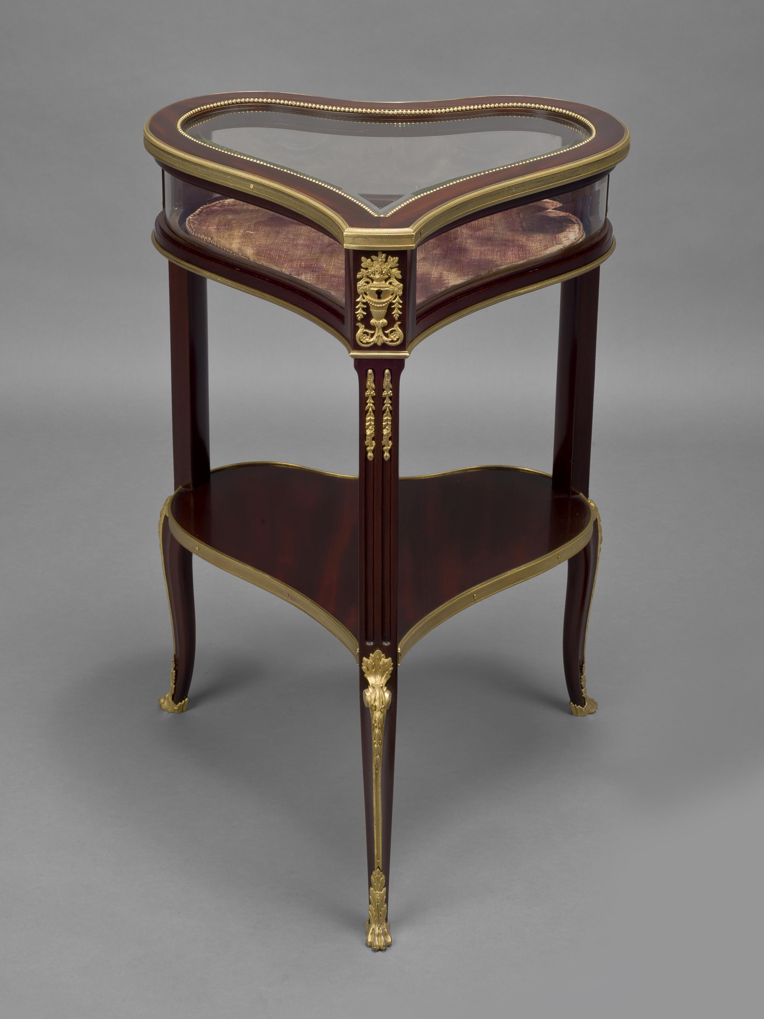 A fine gilt-bronze mounted mahogany table vitrine by Georges-Francois Alix. 

French, circa 1890. 

Stamped to the underside and to the reverse of the gilt-bronze mounts 'Alix'. 

This unusual heart shaped bijouterie table has a hinged glass