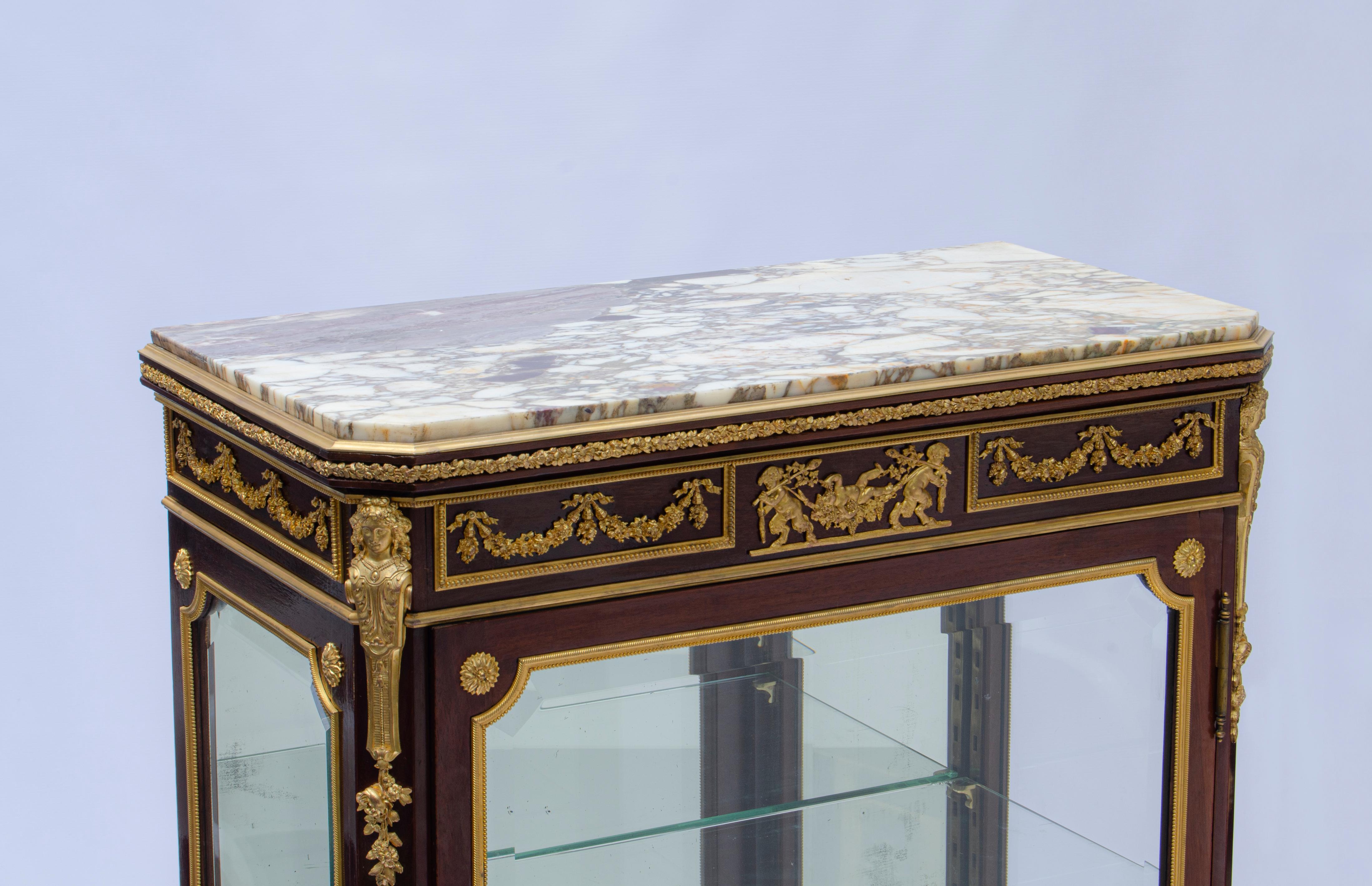 Louis XV style vitrine by François Linke (1855 - 1946) Made of gilt bronze mounted wood, with a violet breccia marble top, front and beveled glass panels on the sides. The central frieze has satyrs leading a drunken bacchus surrounded by ribbon-tied