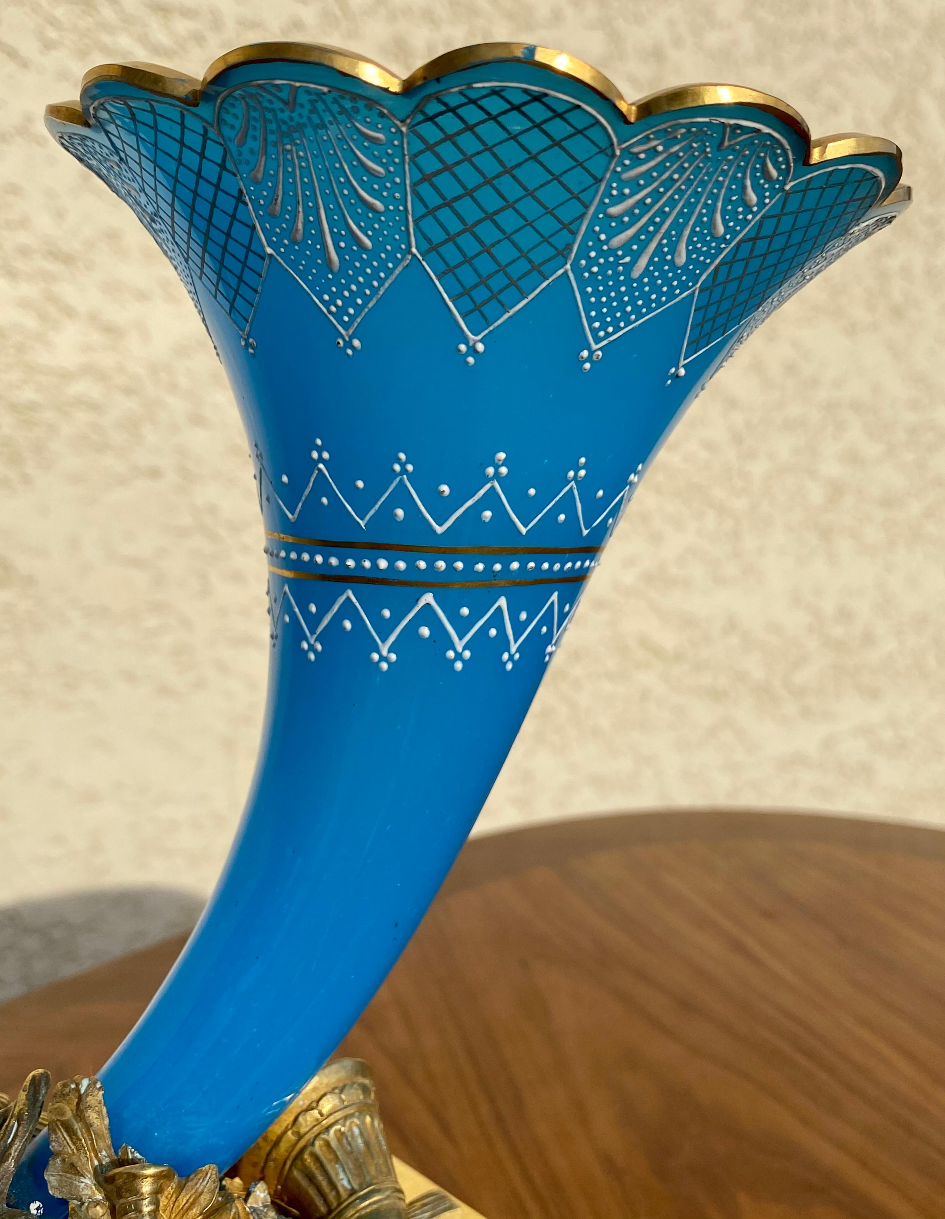 Pezzo raro per questa scultura in bronzo dorato sul tema della caccia. Qui è rappresentata con diversi simboli come questo superbo corno da caccia in opalina blu e oro, un pugnale, una zucca e, al centro, è esposto il trofeo con la testa di un