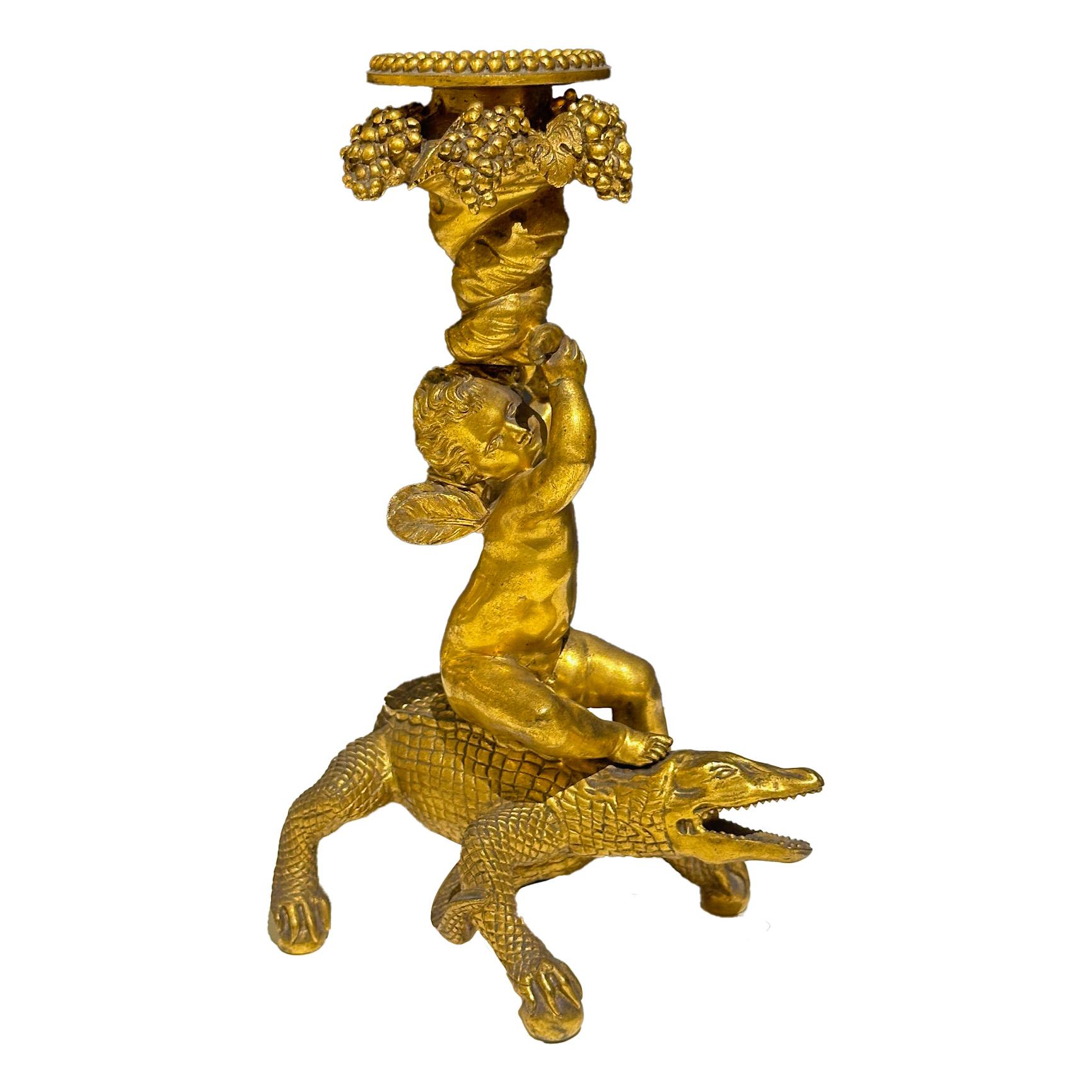 Questa coppia di candelieri in bronzo dorato e cesellato del XIX secolo è una vera e propria testimonianza dell'arte raffinata e decorativa dell'epoca. Le basi dei candelieri sono caratterizzate da coccodrilli attorcigliati, un tocco esotico che
