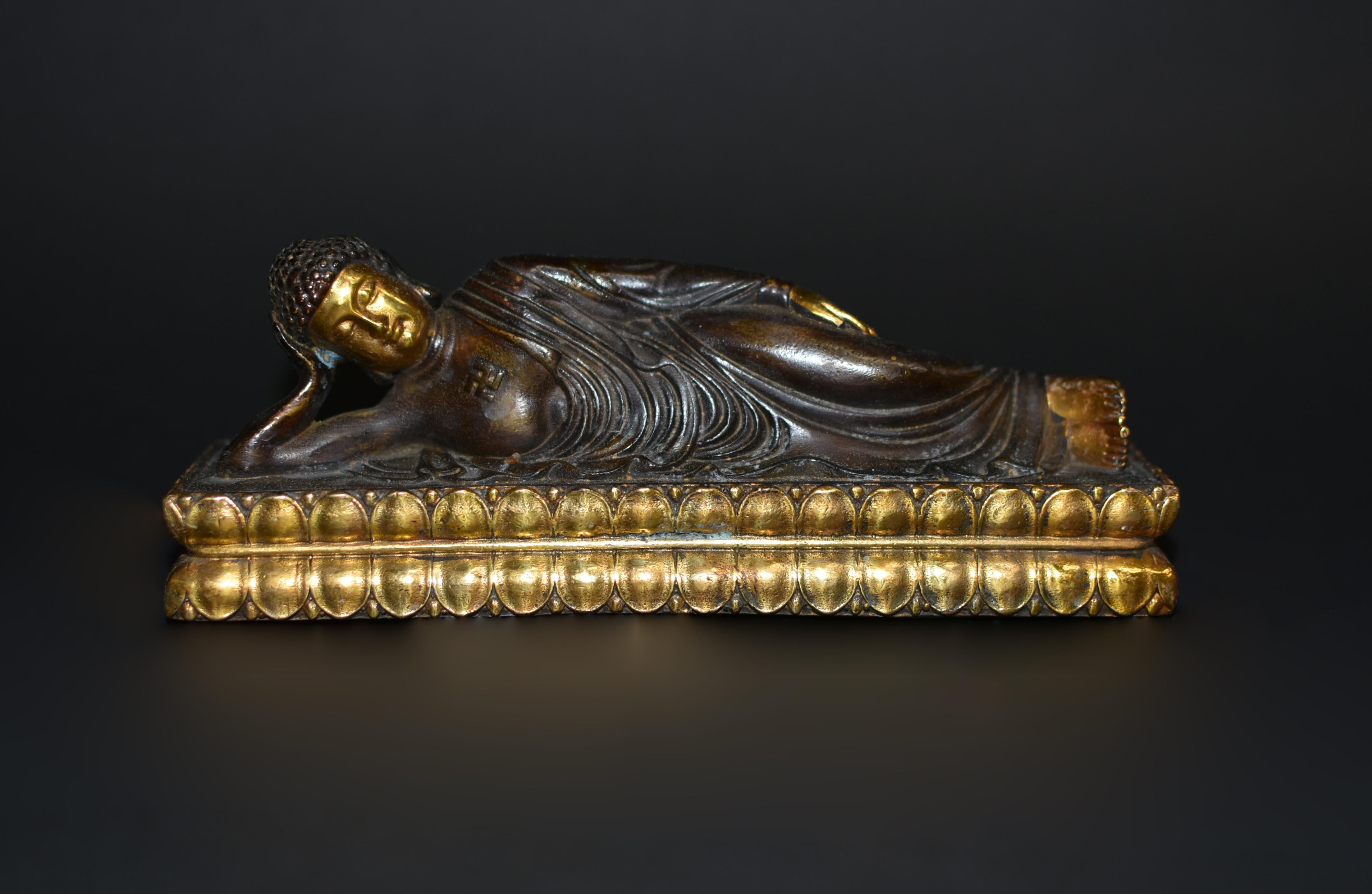 A finely made gilt bronze reclining Buddha. Lying on his right side with flexed feet on double lotus throne, Buddha has Tang style broad face, very serene with closed eyes and long earlobes, neatly coiled hair mounted on top of his hair with