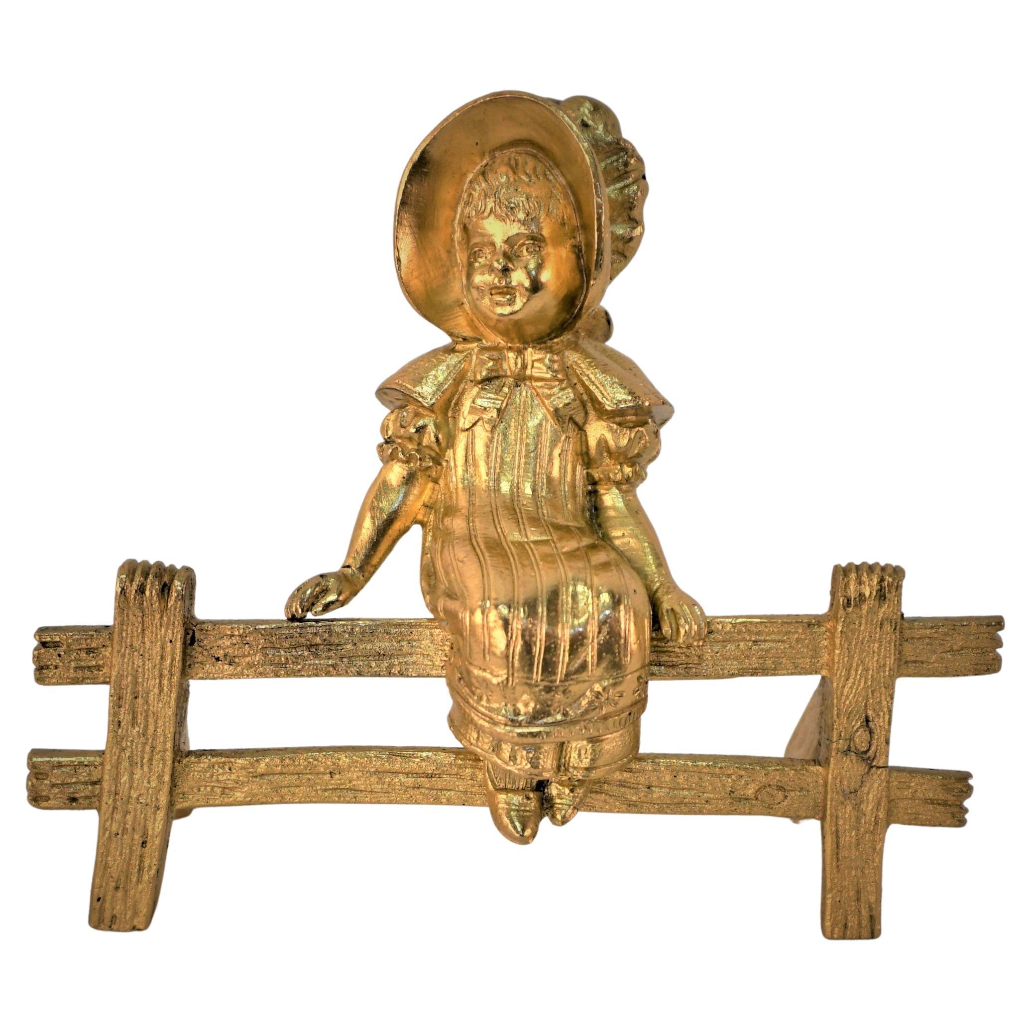 Sculpture en bronze doré, petite fille assise sur une clôture en bois. 